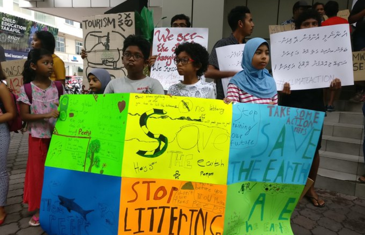 މާލެ: ސެޕްޓެމްބަރު 26، 2019: ތިމާވެއްޓަށް ދޭ ގެއްލުންތަކުން ދުނިޔެ ސަލާމަތް ކުރުމަށް ގޮވާލައި ކުރަމުންދާ ހަޅުތާލުގައި ބައިވެރިވި ކުދިންތަކެއް ތިމާވެށި ހިމާޔަތް ކޮށްދިނުމަށް ގޮވާލާ ހަދާފައިވާ ބޯޑްތަކެއް ހިފައިގެން.-- ފޮޓޯ: ސޭވް މޯލްޑިވްސް