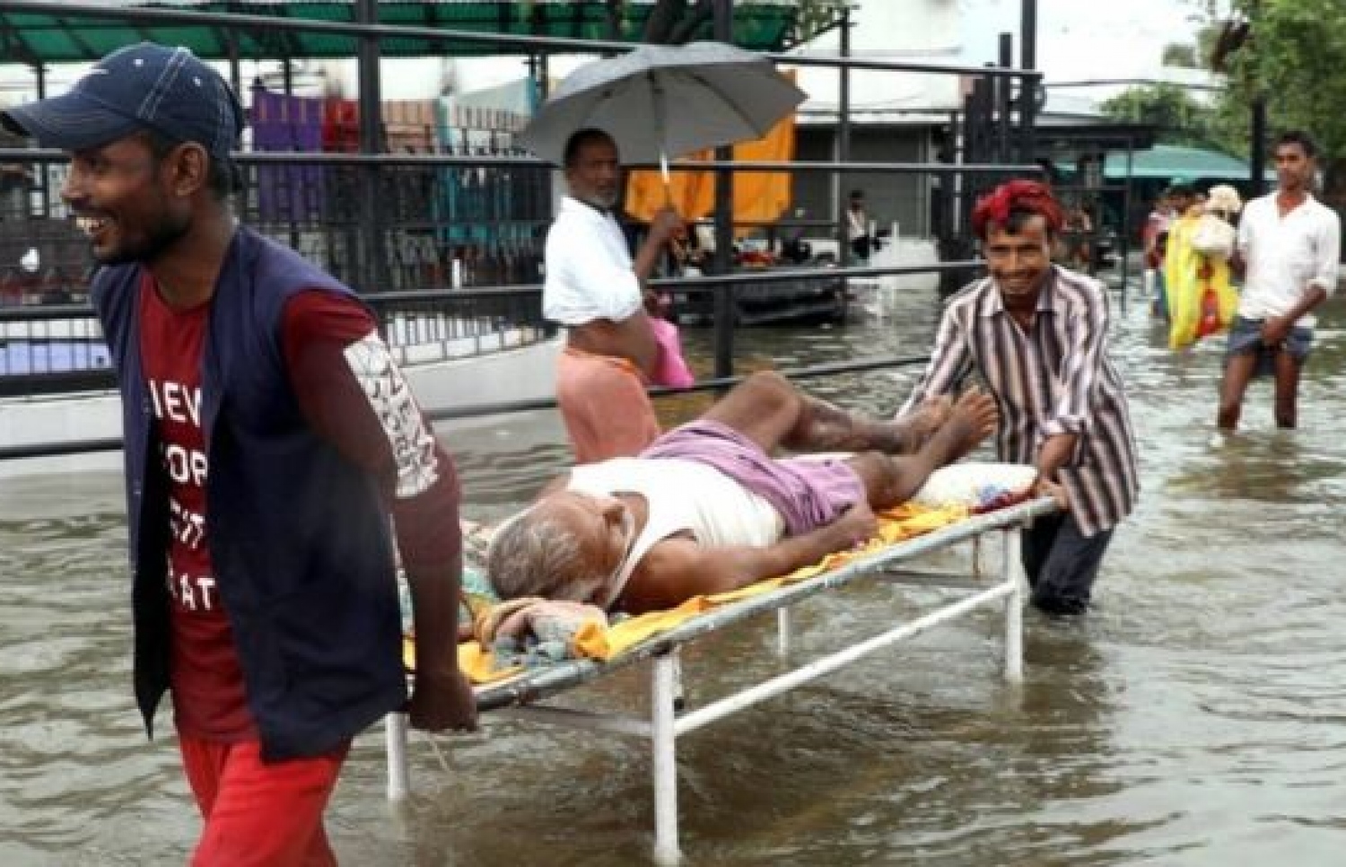 އިންޑިއާގައި ފެންބޮޑުވެފައިވާ ސަރަހައްދަކުން ބަލި މީހަކު އެނދަކަށް ލައިގެން ގެންދަނީ. --ފޮޓޯ: ބީބީސީ ހިންދީ