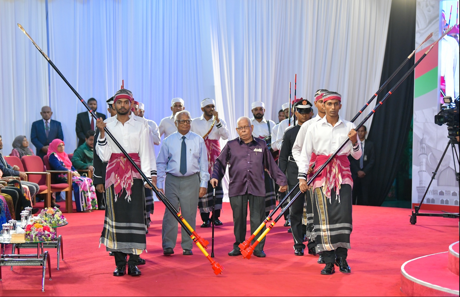 މާލެ: އޮކްޓޯބަރު 29، 2019: ދިވެހިރާއްޖޭގެ ގައުމީ ދުވަހުގެ ރަސްމިއްޔާތުގައި ނިޝާން އިއްޒުއްދީން އިއްޒަތުގެ ވެރިޔާގެ ލަގަބް ލިބިވަޑައިގެންނެވި ދިވެހި ބަހާއި ތާރީޚަށް ދިގު މުއްދަތެއްގައި ޚިދުމަތް ކުރެއްވި އަބްދުﷲ ސޯދިގު (ސޯދުބެ) އާއި ރާއްޖޭގެ ފުރަތަމަ އިންޖިނޭރު ހ.ހިކަރީ އަހުމަދު އާދަމް (ހިކަރީ) ލަގަބު ލިބިގެންނެވުމަށް ރަސްމީ އިއްަތުގައި ސްޓޭޖަށް ވަޑައިގަންނަވަނީ.--- ފޮޓޯ: ހުސައިން ވަހީދު /މިހާރު