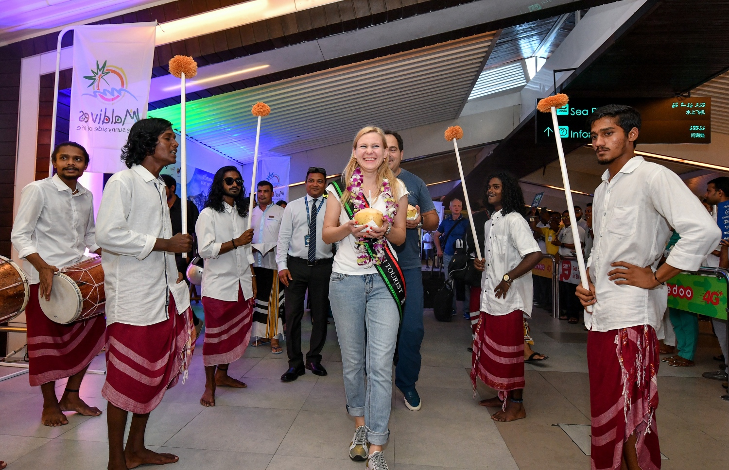 ހުޅުލެ، ވެލާނާ އިންޓަނޭޝަނަލް އެއާޕޯޓު: ނޮވެމްބަރު 24، 2019: ރާއްޖޭގެ ތާރީޚުގައި ފުރަތަމަ ފަހަރަށް އަހަރެއްގެ ތެރޭގައި އައި ޓޫރިސްޓުންގެ އަދަދު ދޮޅު މިލިއަނަށް އެރުމާއި ގުޅިގެން، އެކަން ފާހަގަ ކުރުމަށް ބޭއްވި ހަފުލާގައި 1.5 މިލިއަން ވަނަ ޓޫރިސްޓަކަށް ވި ރަޝިއާގެ އަންހެނެއް ކަމަށް ވާ މަރީނާ ކަޒަކޯވާ އަށް ސަގާފީ ބޮޑުބެރަކާއެކު މަރުހަބާ ކިޔަނީ.-- ފޮޓޯ: ނިޝާން އަލީ /މިހާރު