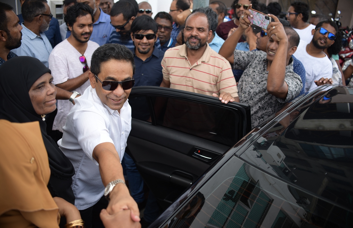 މާލެ: ނޮވެމްބަރު 28، 2019: ކުރީގެ ރައީސް ޔާމީނަށް ހުކުމް އިއްވުމުގެ ޝަރީއަތަށް ކްރިމިނަލް ކޯޓަށް ވަޑައިގަތުމުގެ ކުރިން އެމަނިކުފާނުގެ ސަޕޯޓަރުންނާ ސަލާމް ކުރައްވަނީ.---ފޮޓޯ: ނިޝާން އަލީ/މިހާރު