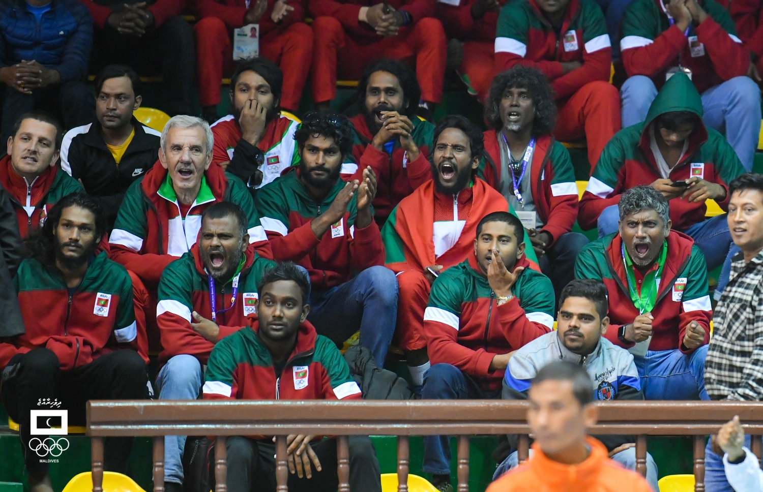 ގައުމީ އަންހެން ޓީމުގެ ކުޅުންތެރިން ކުޅުނު މެޗުގައި ޓީމަށް ހިތްވަރުދިނުމުގައި ގައުމީ ފިރިހެން ޓީމުގެ ކުޅުންތެރިންނާއި އޮފިޝަލުން. -- ފޮޓޯ: ހުސެއިން ވަހީދު/ މޯލްޑިވްސް އޮލިމްޕިކް ކޮމިޓީ