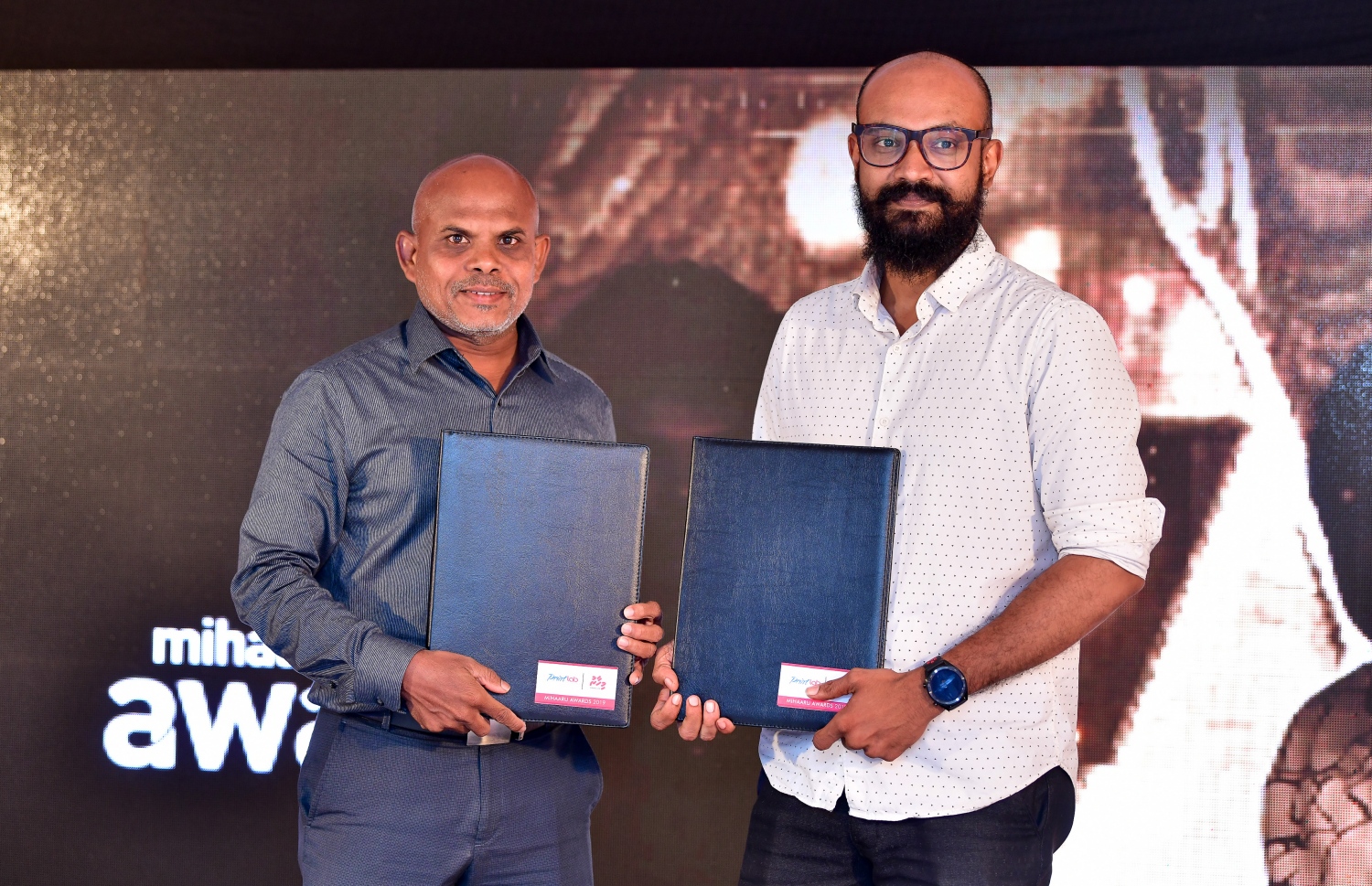 މާލެ: ޑިސެމްބަރު 22، 2019: ރާއްޖޭގެ ކުޅިވަރުގައި ދެވޭ އެންމެ ޝަރަފްވެރި އަދި އެންމެ ބޮޑު އެވޯޑްސް ކަމަށްވާ މިހާރު އެވޯޑްސްގެ މި އަހަރުގެ އިވެންޓުގެ ސްޕޮންސަރުންނާ އެކު އެއްބަސްވުމުގައި ސޮއިކުރުމަށް ބޭއްވި ރަސްމިއްޔާތުގައި މިހާރުގެ އެޑިޓަރު މޫސާ ލަތީފް (ވ) އާއި ޕްރިންޓް ލެބްގެ ކްރިއޭޓިވް ޑައިރެކްޓަރު މުހައްމަދު އާބިދު ސައީދެ އެއްބަސްވުން ދައްކާލަނީ --. ފޮޓޯ:ނިޝާން އަލީ/މިހާރު