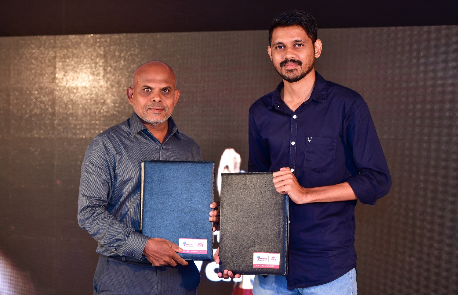 މާލެ: ޑިސެމްބަރު 22، 2019: ރާއްޖޭގެ ކުޅިވަރުގައި ދެވޭ އެންމެ ޝަރަފްވެރި އަދި އެންމެ ބޮޑު އެވޯޑްސް ކަމަށްވާ މިހާރު އެވޯޑްސްގެ މި އަހަރުގެ އިވެންޓުގެ ސްޕޮންސަރުންނާ އެކު އެއްބަސްވުމުގައި ސޮއިކުރުމަށް ބޭއްވި ރަސްމިއްޔާތުގައި މިހާރުގެ އެޑިޓަރު މޫސާ ލަތީފް (ވ) އާއި ވީޓިވީގެ ޑެޕިއުޓީ ހެޑް އޮފް ވީ ސްޕޯޓްސް އިސްމާއިލް ޝާހު އެއްބަސްވުން ދައްކާލަނީ--. ފޮޓޯ:ނިޝާން އަލީ/މިހާރު