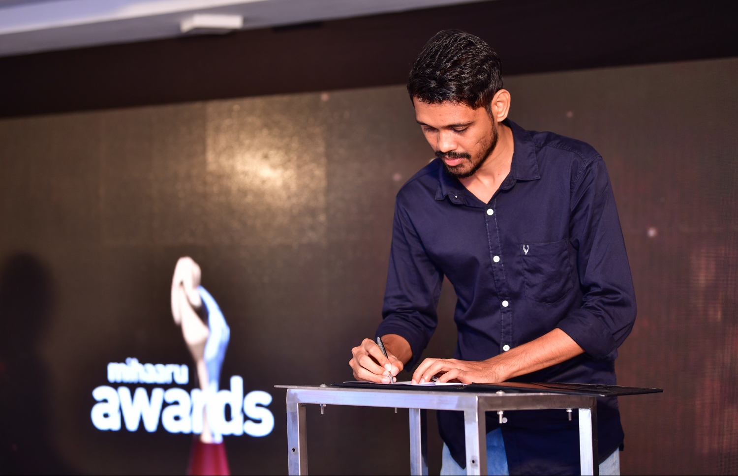 މާލެ: ޑިސެމްބަރު 22، 2019: ރާއްޖޭގެ ކުޅިވަރުގައި ދެވޭ އެންމެ ޝަރަފްވެރި އަދި އެންމެ ބޮޑު އެވޯޑްސް ކަމަށްވާ މިހާރު އެވޯޑްސްގެ މި އަހަރުގެ އިވެންޓުގެ ސްޕޮންސަރުންނާ އެކު އެއްބަސްވުމުގައި ސޮއިކުރުމަށް ބޭއްވި ރަސްމިއްޔާތުގައި ވީޓިވީގެ ޑެޕިއުޓީ ހެޑް އޮފް ވީ ސްޕޯޓްސް އިސްމާއިލް ޝާހު އެއްބަސްވުމުގައި ސޮއިކުރަނީ--. ފޮޓޯ:ނިޝާން އަލީ/މިހާރު