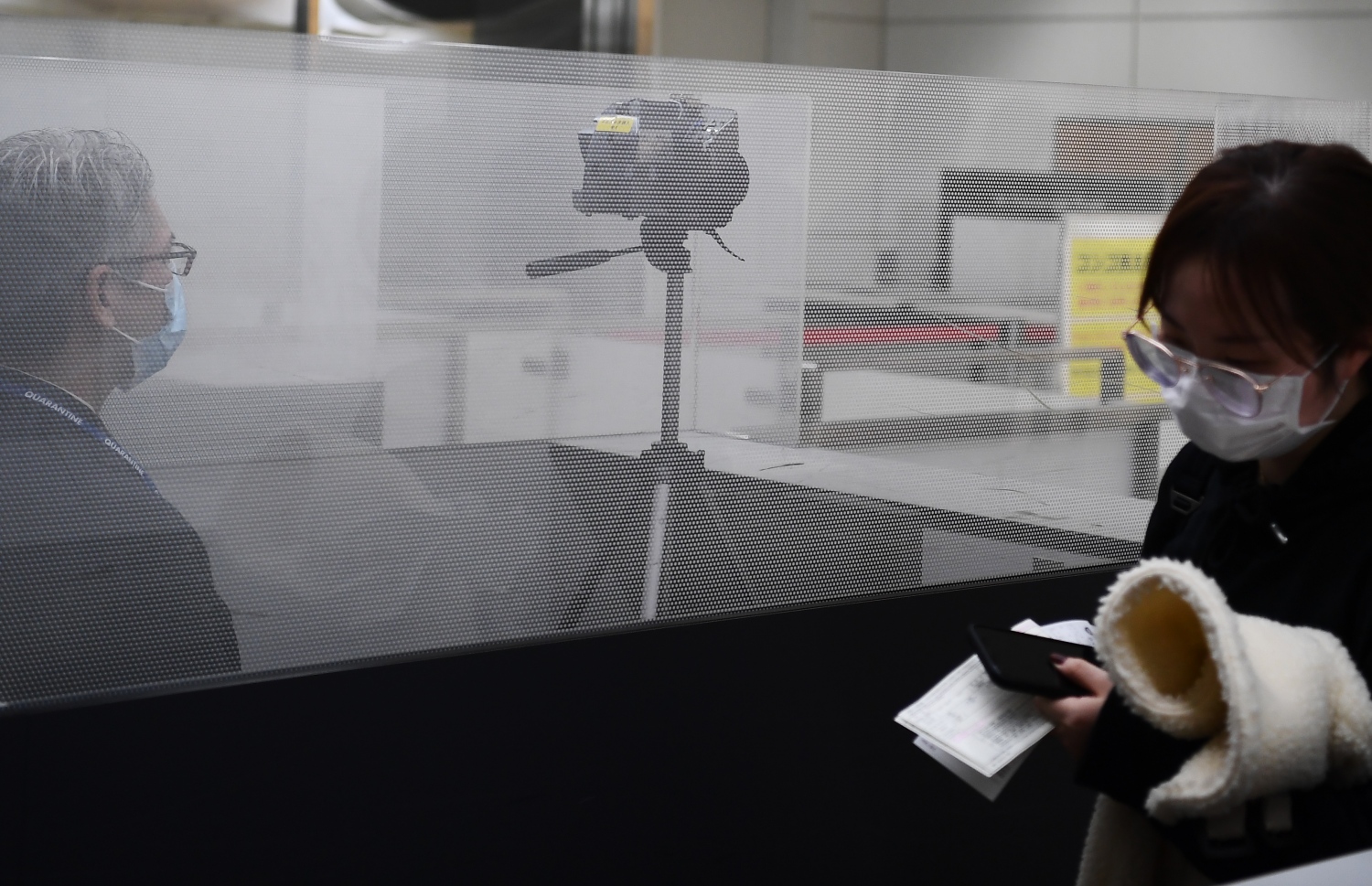 ވުހާން ސިޓީން ދަތުރު ކުރި މީހަކު ޖަޕާނުގެ ނަރީޓާ އެއާޕޯޓުގައި ސްކްރީން ކުރަނީ. --ފޮޓޯ:އޭއެފްޕީ