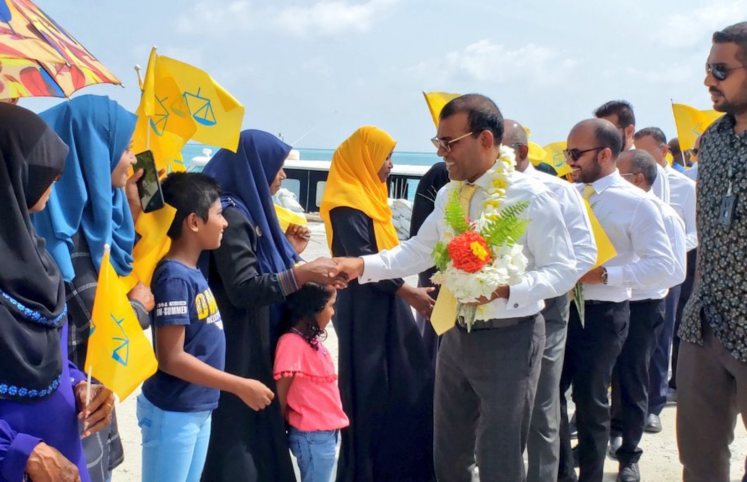 ލޯކަލް ކައުންސިލްގެ އިންތިޚާބަށް ރައްޔިތުންގެ މަޖިލީހުގެ ރައީސް މުހައްމަދު ނަޝީދާއި އެމްޑީޕީގެ އިސްވެރިން ކުރައްވާ ކެމްޕެއިން ދަތުރުގައި ރަށެއްގެ ރައްޔިތުން މަރުހަބާ ކިޔަނީ. --- ފޮޓޯ: އެމްޑީޕީ