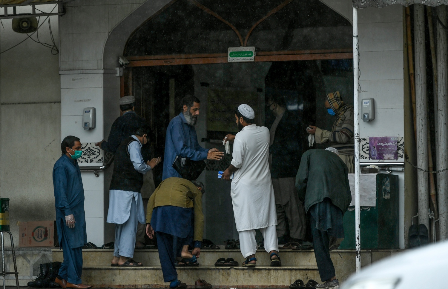 އިސްލާމްއާބާދުގެ މިސްކިތަކަށް އިއްޔެ ދިޔަ މީހުން މިސްކިތަށް ވަނުމުގެ ކުރިން އަތުގައި ސެނިޓައިޒާ އުނގުޅަނީ. -ފޮޓޯ:އޭއެފްޕީ