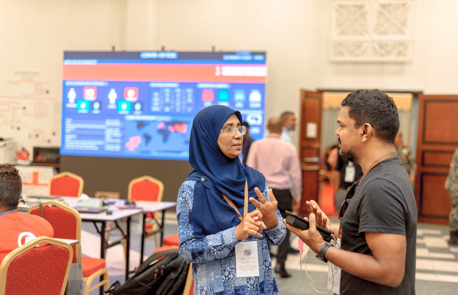 ޑިރެކްޓަ ޖެނެރަލް އޮފް ޕަބްލިކް ހެލްތު މައިމޫނާ އަބޫބަކުރު، ހެލްތު މިނިސްޓްރީގެ އޮފިޝަލަކާ ނޭޝަނަލް އިމަޖެންސީ އޮޕަރޭޝަން ސެންޓަރުގައި ވާހަކަ ދައްކަވަނީ: ކޮރޯނާވައިރަސް ފެތުރުން ކޮންޓްރޯލް ކުރުމަށްޓަކައި ފިޔަވަޅުތައް އެޅުމަށްޓަކައި ސިއްހީ ނުރައްކަލުގެ ކުއްލި ހާލަތު ރާއްޖޭގައި އިއުލާން ކޮށްފައިވާއިރު، އާންމު ސިއްހަތާ ބެހޭ ގާނޫނުގެ ދަށުން ޑިރެކްޓަ ޖެނެރަލްގެ މަގާމުގެ ހައިސިއްޔަތުން މައިމޫނާ އަށް ބޮޑެތި ބާރުތަކެއް ލިބިދީފައިވޭ.---ފޮޓޯ: ހެލްތު މިނިސްޓްރީ