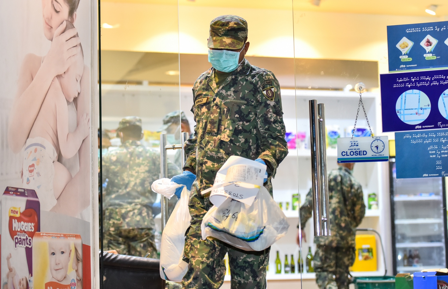 މާލެ: އޭޕްރިލް 17، 2020: އެސްޓީއޯ އިން ގޭގެ އަށް ޑެލިވަކޮށްދޭންޖެހޭ މުދާ ގިނަވެ ބާރުބޮޑުވުމާ އެކު މުދާ އުފުލައިދިނުމަށް މުދަލާއެކު ސިފައިންގެ މީހަކު އެސްޓީއޯ ސުޕަމާޓުން ނުކުންނަނީ.-- ފޮޓޯ: އަހުމަދު އަވްޝަން /މިހާރު