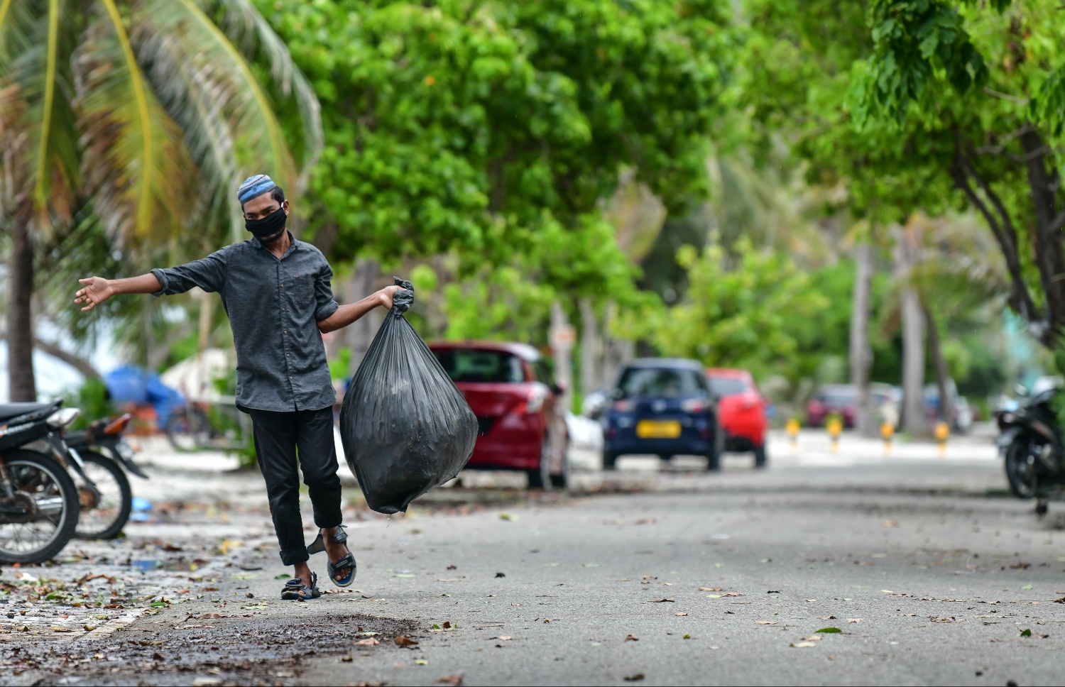 ހުޅުމާލެ: މެއި 21، 2020- ހުޅުމާލޭގައި އުޅޭ ބިދޭސީއަކު ރައްކާތެރިވުމުގެ ގޮތުން މާސްކް އަޅައިގެން ކުނިކޮތަޅެއް ހިފައިގެން ދަނީ.---ފޮޓޯ: ނިޝާން އަލީ/މިހާރު