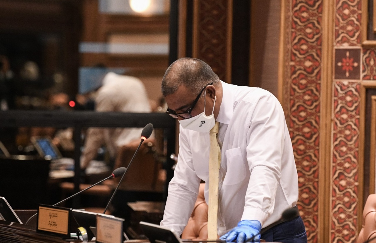 މާލެ: މެއި 26، 2020: މަޖިލިސް މެމްބަރުން މިއަދުގެ ޖަލްސާގައި ބިލެއްދޫ ދާއިރާގެ މެމްބަރު ވާހަކަ ދައްކަވަނީ: މެމްބަރުން ތިއްބެވީ މާސްކު އަޅުއްވައިގެން، ހާއްސަ އިންތިޒާމެއްގެ ތެރެއިން ދުރުދުރުގައި-- ފޮޓޯ: މަޖިލިސް