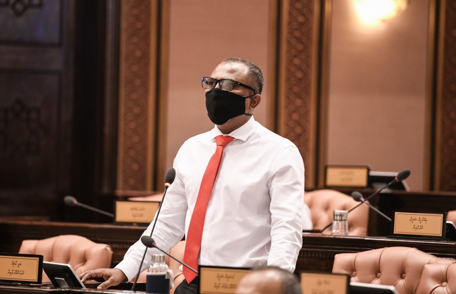 މާލެ: މެއި 26، 2020: މަޖިލިސް މެމްބަރުން މިއަދުގެ ޖަލްސާގައި މެމްބަރު އަލީ އާޒިމް ވާހަކަ ދައްކަވަނީ: މެމްބަރުން ތިއްބެވީ މާސްކު އަޅުއްވައިގެން، ހާއްސަ އިންތިޒާމެއްގެ ތެރެއިން ދުރުދުރުގައި-- ފޮޓޯ: މަޖިލިސް