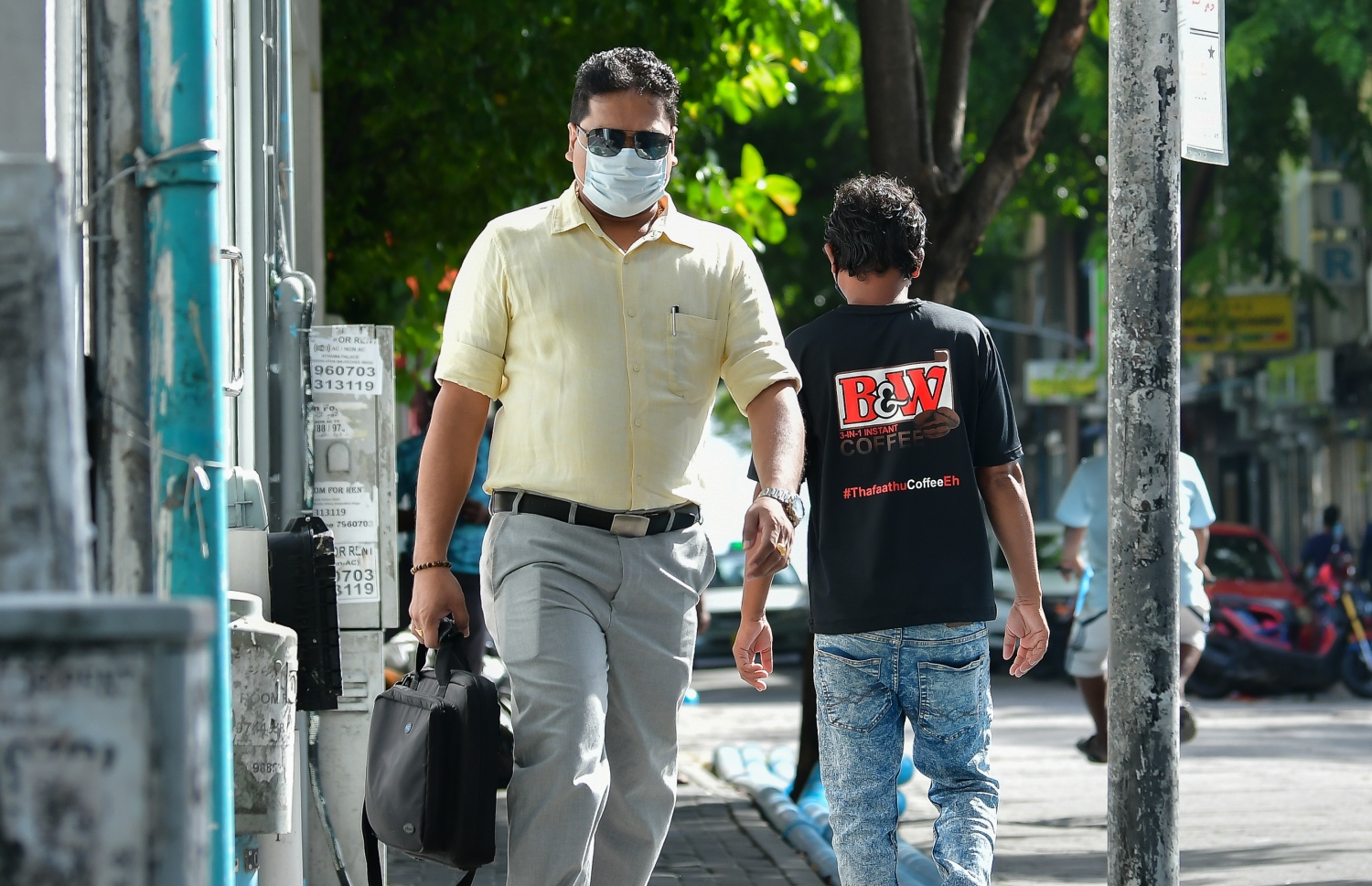 ދެ މަހުގެ ބަންދަކަށް ފަހު، އޮފީސްތައް ހުޅުވުމާ އެކު، މީހަކު މާސްކު އަޅައިގެން ހިނގާފައި ދަނީ.-- ފޮޓޯ: ނިޝާން އަލީ /މިހާރު