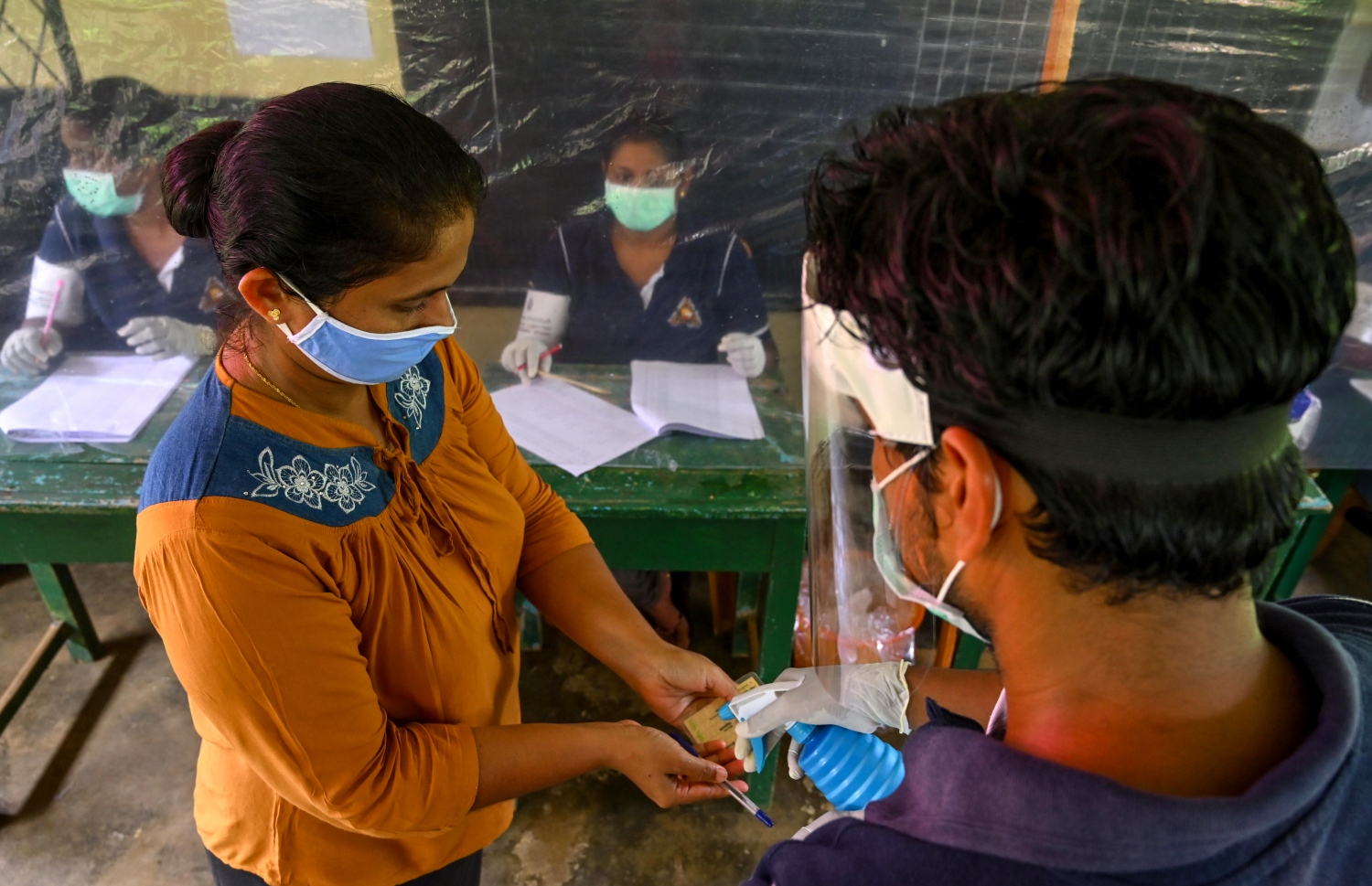 ލަންކާގައި އިއްޔެ ބޭއްވި ނަމޫނާ އިންތިޚާބުގައި ވޯޓުލާން ދިޔަ މީހެއްގެ އަތަށް ޑިސްއިންފެކްޓެންޓް ސްޕްރޭ ކުރަނީ. --ފޮޓޯ:އޭއެފްޕީ