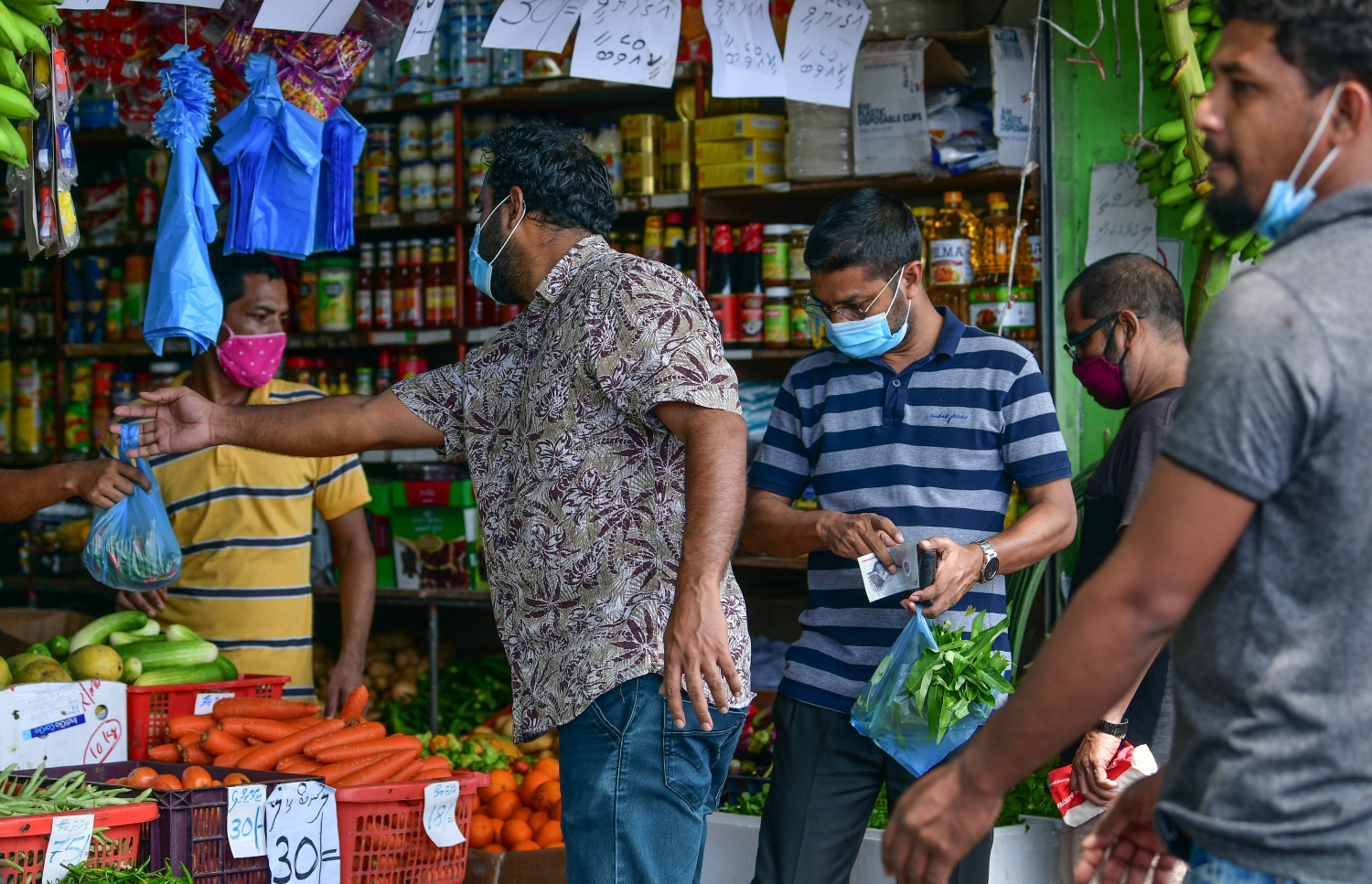 ބަޔަކު ބާޒާރުމަތީ ފިހާރައަކުން ވިޔަފާރި ކުރަނީ: މާސްކް އަޅައިގެން ތިއްބަސް ގައިދުރުކަމެއް ނުބަހައްޓާ-- ފޮޓޯ: ނިޝާން އަލީ/މިހާރު