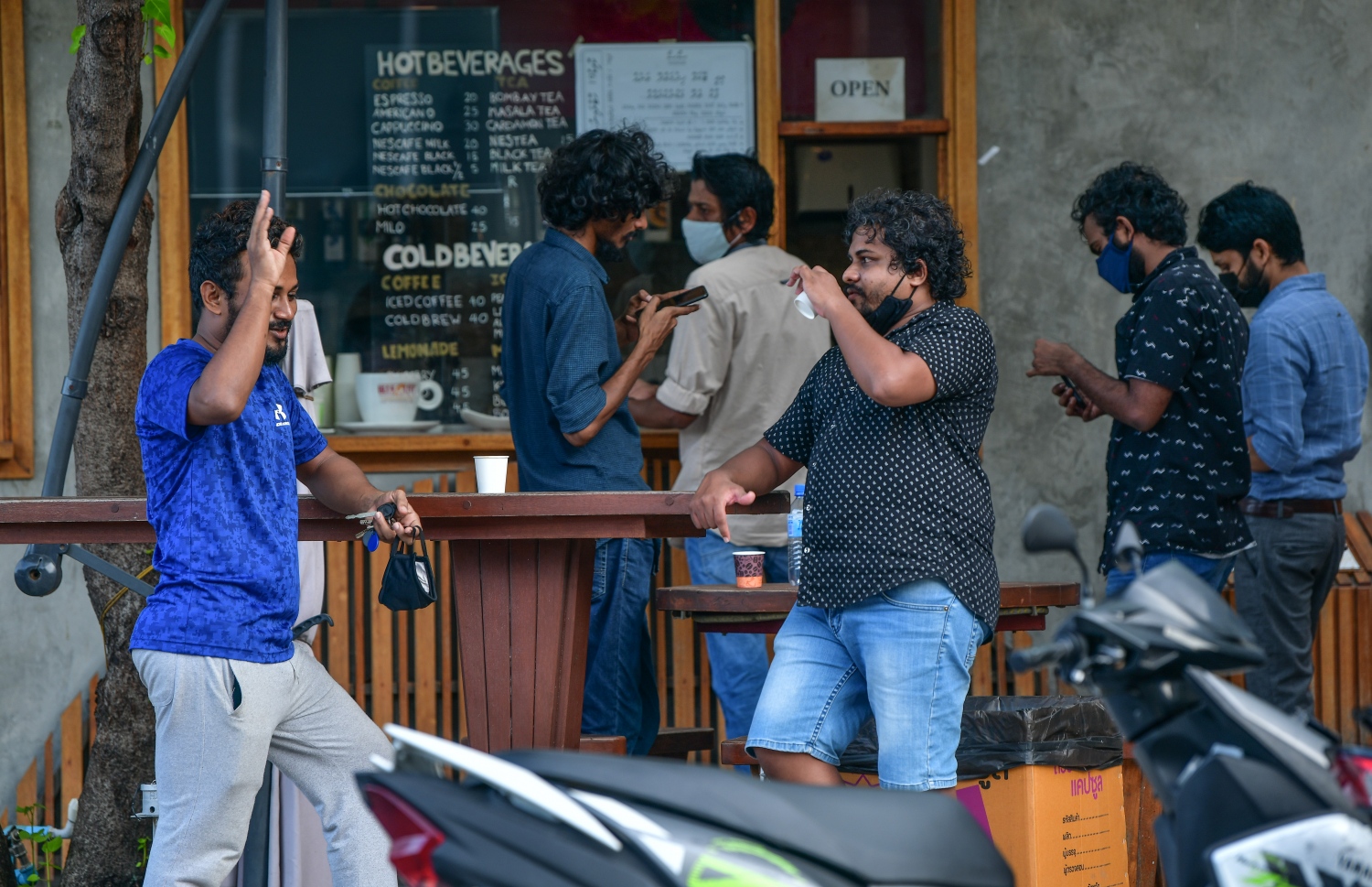 މާލެ: ޖޫން 21، 2020: މާލެ ސަރަހައްދަށް އިއުލާން ކޮށްފައިވާ ލޮކްޑައުން އަށް ލުޔެއް ދިނުމާއެކު، ކޮފީ ޝޮޕެއް ކައިރީގައި ބަޔަކު އެއްތަނެއްގައި އެއްވެސް ގައިދުރު ކުރުމެއް ނެތި މަޑުކޮށްލައިގެން.-- ފޮޓޯ: ނިޝާން އަލީ /މިހާރު