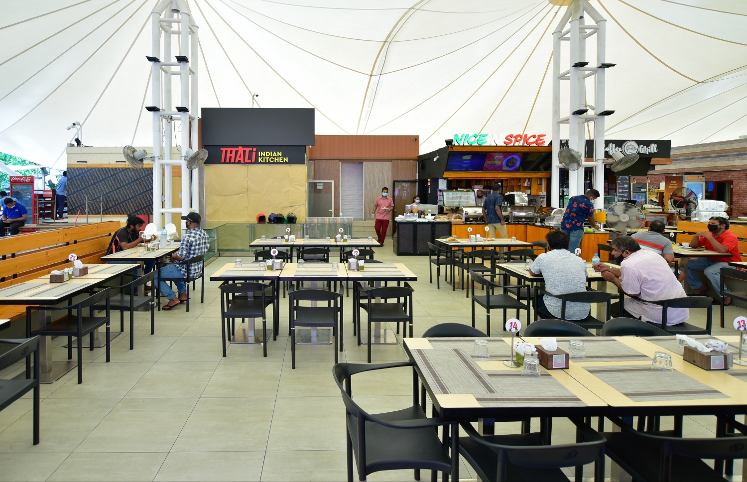 މާލެ: ޖުލައި 1، 2020: ކޮވިޑް-19 އާ ގުޅިގެން އެޅި ރައްކާތެރިކަމުގެ ފިޔަވަޅުތަކުގެ ތެރޭގައި ކެއުންބުއިމުގެ ހިދުމަތް ދޭ ތަންތަނަށް މީހުން ވަނުން މަނާކުރިތާ ތިން މަހަށް ވުރެ ގިނަ ދުވަހަށްފަހު، މާލެ އާއި ހުޅުމާލެ އާއި ވިލިމާލޭގައި، އަލުން އާންމުންނަށް ހޮޓާ/ރެސްޓޯރެންޓް/ކެފޭތައް ހުޅުވާލުމާއެކު ބަޔަކު ފުޑް ކޯޓުގައި ކޮފީ ބޮނީ.-- ފޮޓޯ: އަހުމަދު އަވްޝަން /މިހާރު