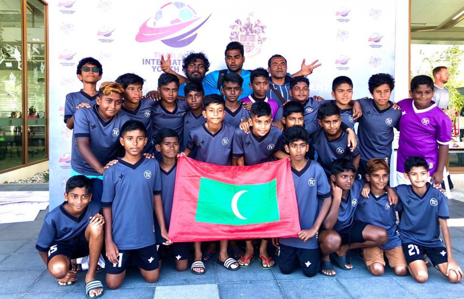 ޓީސީ އެކެޑަމީ ކުޅުންތެރިން މިދިޔަ ޑިސެމްބަރު މަހު ތައިލެންޑްގައި އޮތް މުބާރާތުގެ ތެރެއިން. ކޯޗު ސޮބާ އާއި ޔޫއްޓޭ އެ ކުޅުންތެރިންނާ އެކު.-- ފޮޓޯ: ޓީސީ އެކެޑަމީ/ ފޭސްބުކް