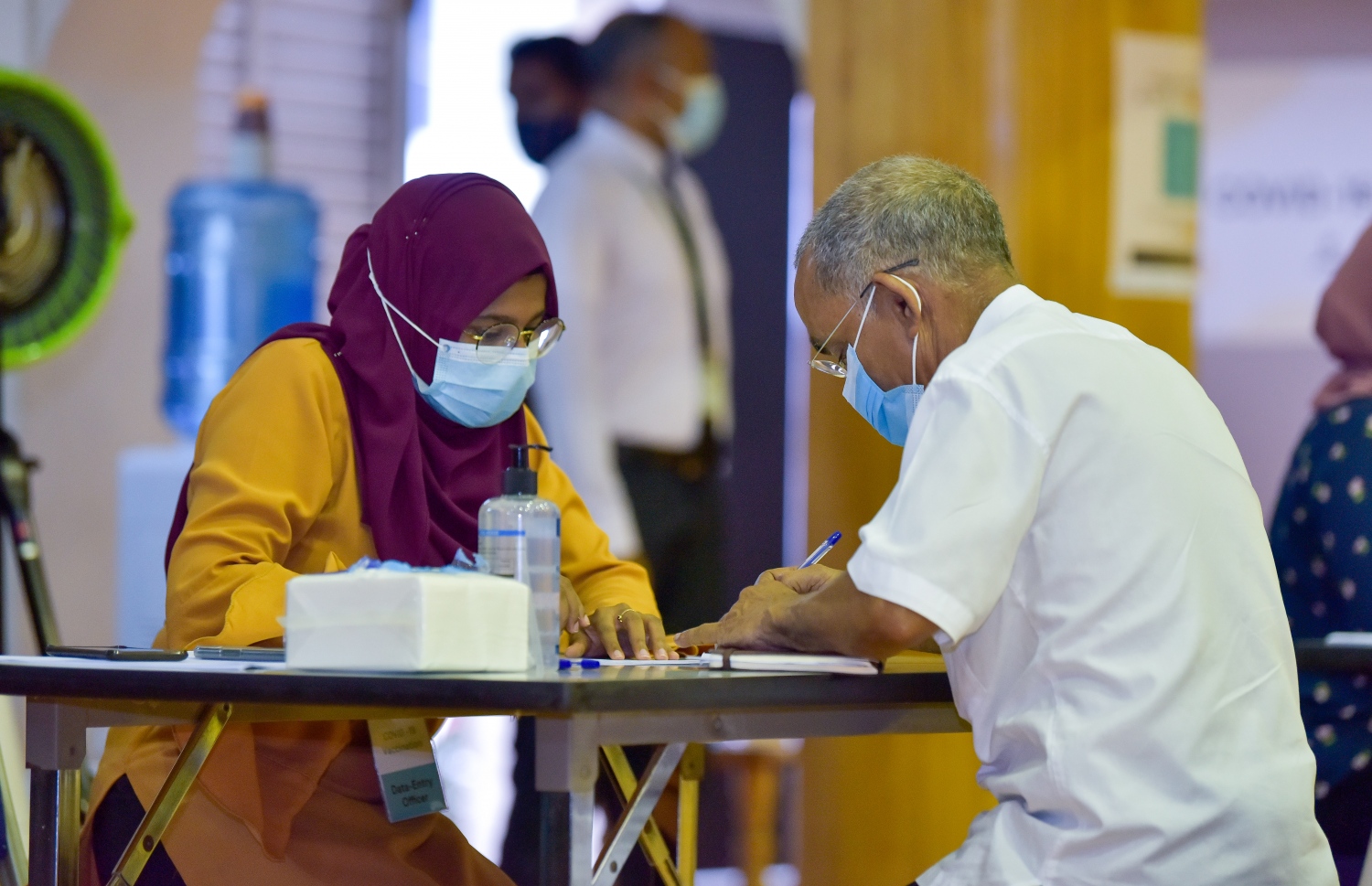 މާލެ: ފެބްރުއަރީ 1، 2021: ރާއްޖޭގައި ކޮވިޑް-19 ވެކްސިން ދިނުމުގެ ޕްރޮގްރާމްގައި ވެކްސިން ދިނުމުގެ ކުރިން ލިޔެކިޔުންތައް ފުރިހަމަ ކުރަނީ.-- ފޮޓޯ: އަހުމަދު އަވްޝަން އިލްޔާސް /މިހާރު