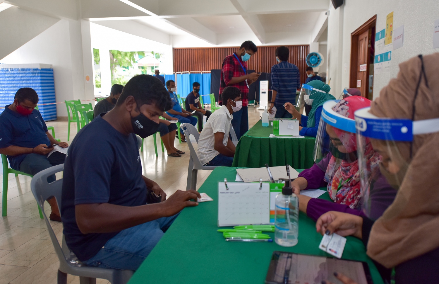 މާލެ: ފެބްރުއަރީ 25، 2021: ލިޔެކިޔުންނެތް ބިދޭސީއެއް ވެކްސިން ޖެހުމުގެ ކުރިން ފުރަންޖެހޭ މައުލޫމާތު ފޯމު ފުރަނީ.-- ފޮޓޯ: އަހުމަދު އަވްޝަން އިލްޔާސް /މިހާރު