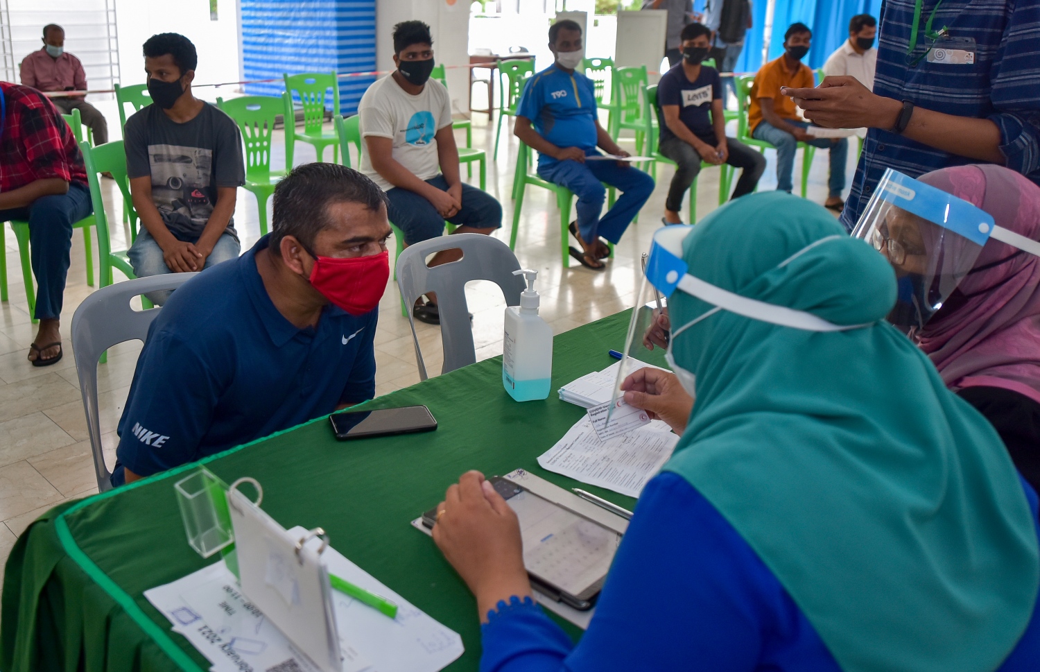 މާލެ: ފެބްރުއަރީ 25، 2021: ލިޔެކިޔުންނެތް ބިދޭސީއެއް ވެކްސިން ޖެހުމުގެ ކުރިން ފުރަންޖެހޭ މައުލޫމާތު ފޯމު ފުރަނީ.-- ފޮޓޯ: އަހުމަދު އަވްޝަން އިލްޔާސް /މިހާރު