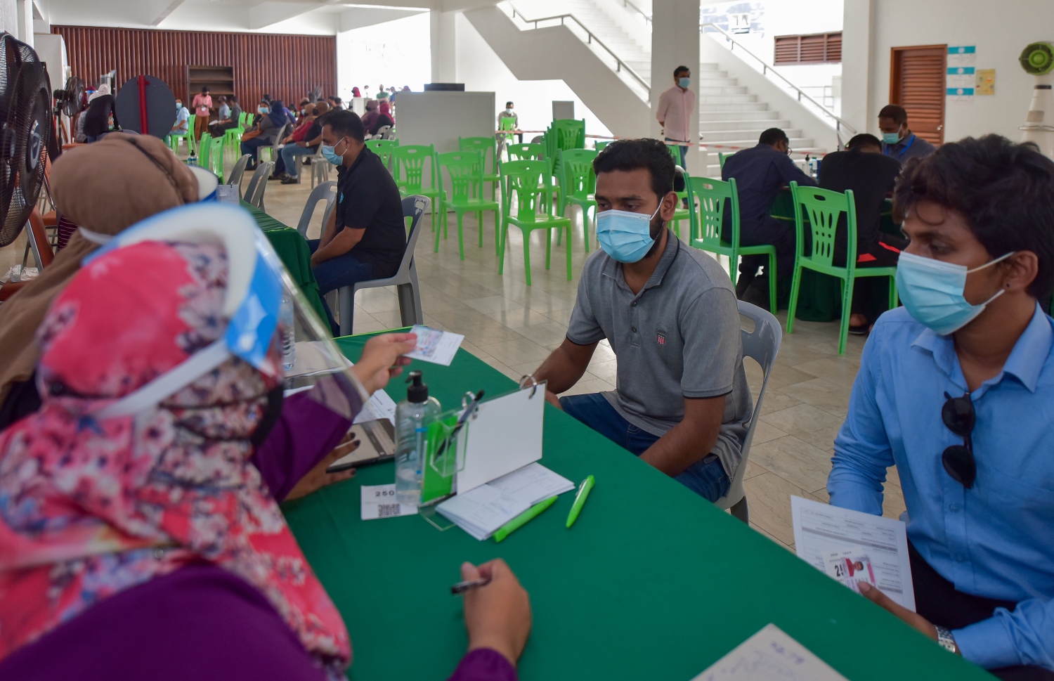މާލެ: ފެބްރުއަރީ 25، 2021: ލިޔެކިޔުންނެތް ދެ ބިދޭސީއަކު ވެކްސިން ޖެހުމުގެ ކުރިން ފުރަންޖެހޭ މައުލޫމާތު ފޯމު ފުރަނީ.-- ފޮޓޯ: އަހުމަދު އަވްޝަން އިލްޔާސް /މިހާރު