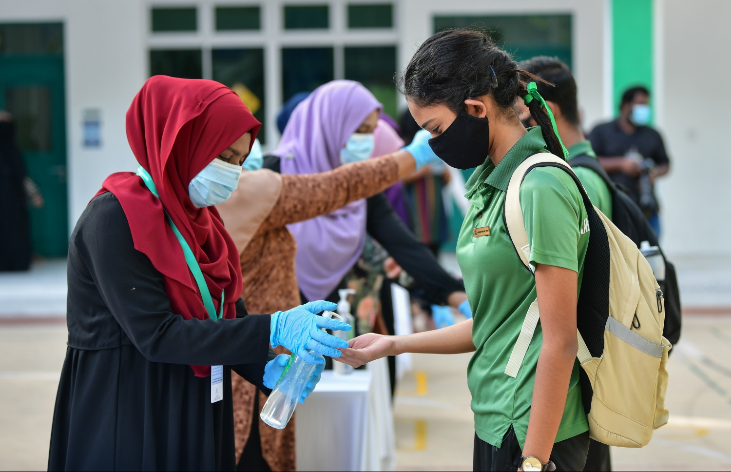 ކޮވިޑް ބޮޑު ބަންދަށް ފަހު ދަރިވަރުން ސްކޫލަށް ދިއުމުން އަމީނިއްޔާ ސްކޫލުގެ އަންހެން ޓީޗަރަކު ދަރިވަރުން އަތަށް ސެނެޓައިޒާ އަޅައިދެނީ--.ފޮޓޯ: ނިޝާން އަލީ/މިހާރު