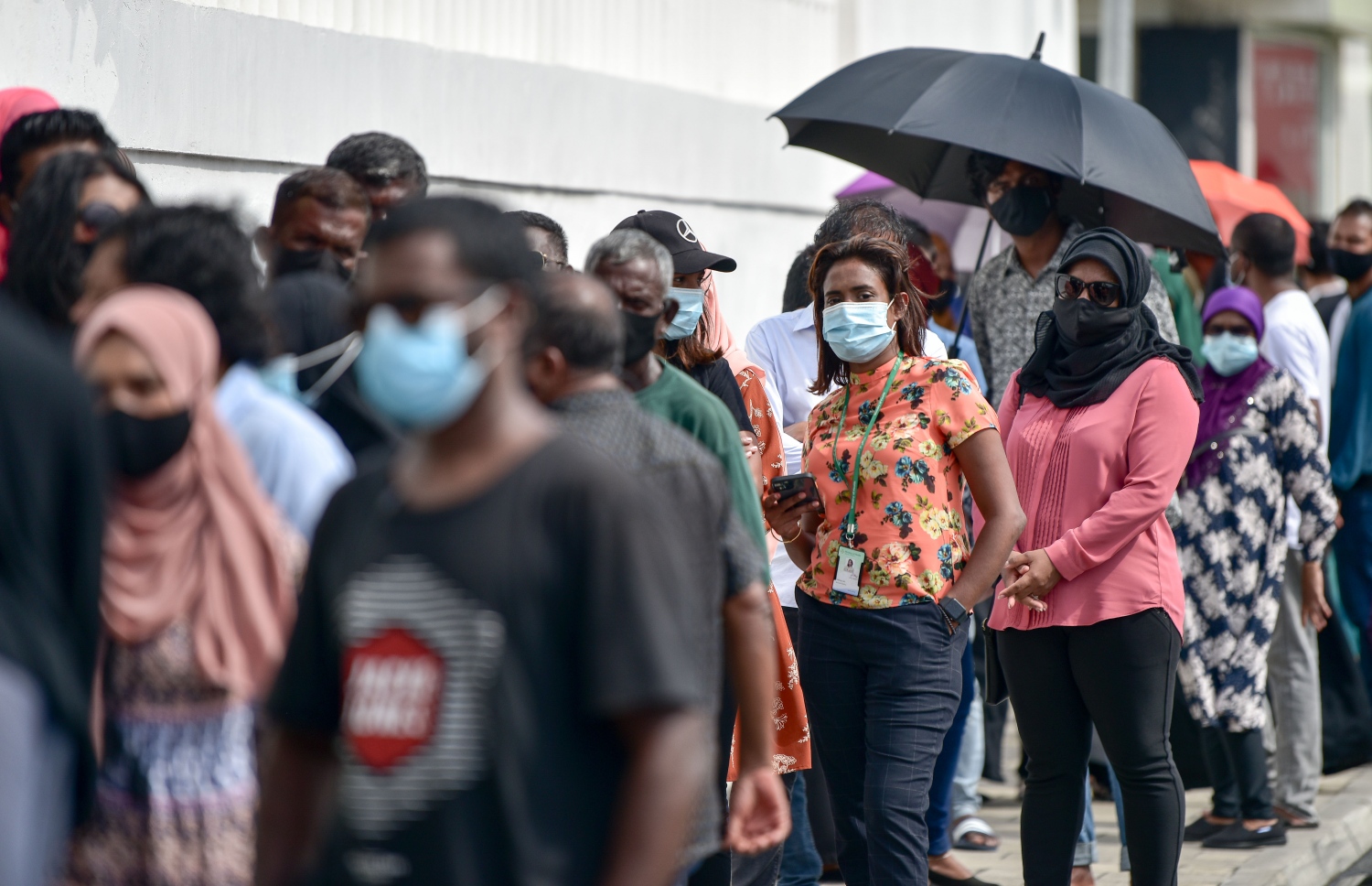 މާލެ- މާޗް 14، 2021: ކޮވިޑް ވެކްސިން ޖަހަން ސޯޝަލް ސެންޓަރު ބޭރުގައި މިއަދު ހެނދުނު އެތައް ސަތޭކަ ބަޔަކު ކިއޫގައި، ވެކްސިންގެ ފުރަތަމަ ޑޯޒް އާންމުކޮށް ޖަހައިދިނުން މާދަމާ ހުއްޓާލާތީ މިއަދުވެސް ވެކްސިން ސެންޓަރުތަކަށް ބާރު ބޮޑުވެ އެތައް ސަތޭކަ ބަަޔަކާ އެކު ކިއޫތައް ވަނީ ދަމާލައިފައި--. ފޮޓޯ:ނިޝާން އަލީ/މިހާރު