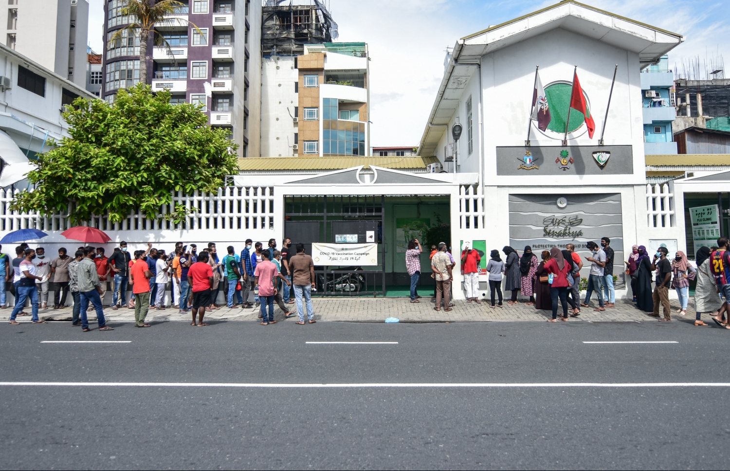 މާލެ- މާޗް 14، 2021: ކޮވިޑް ވެކްސިން ޖަހަން ސޯޝަލް ސެންޓަރު ބޭރުގައި މިއަދު ހެނދުނު އެތައް ސަތޭކަ ބަޔަކު ކިއޫގައި، ވެކްސިންގެ ފުރަތަމަ ޑޯޒް އާންމުކޮށް ޖަހައިދިނުން މާދަމާ ހުއްޓާލާތީ މިއަދުވެސް ވެކްސިން ސެންޓަރުތަކަށް ބާރު ބޮޑުވެ އެތައް ސަތޭކަ ބަަޔަކާ އެކު ކިއޫތައް ވަނީ ދަމާލާފައި--. ފޮޓޯ:ނިޝާން އަލީ/މިހާރު