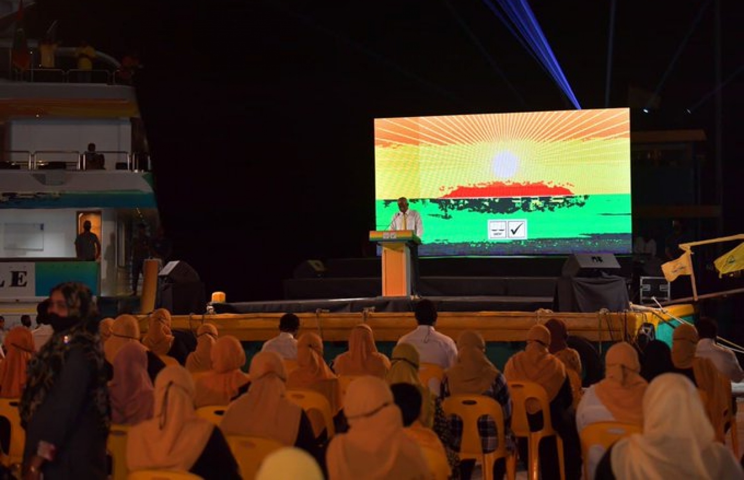 ރަސްދޫ ބަނދަރުގައި އޮތް ދޯންޏެއްގައި ހުންނަވައިގެން ރައީސް ވާހަކަފުޅު ދައްކަވާއިރު، ރަށުގެ އަތިރިމަތީގައި ގިނަ ބަޔަކު އަޑުއަހަނީ-- ފޮޓޯ: ރައީސް އޮފީސް