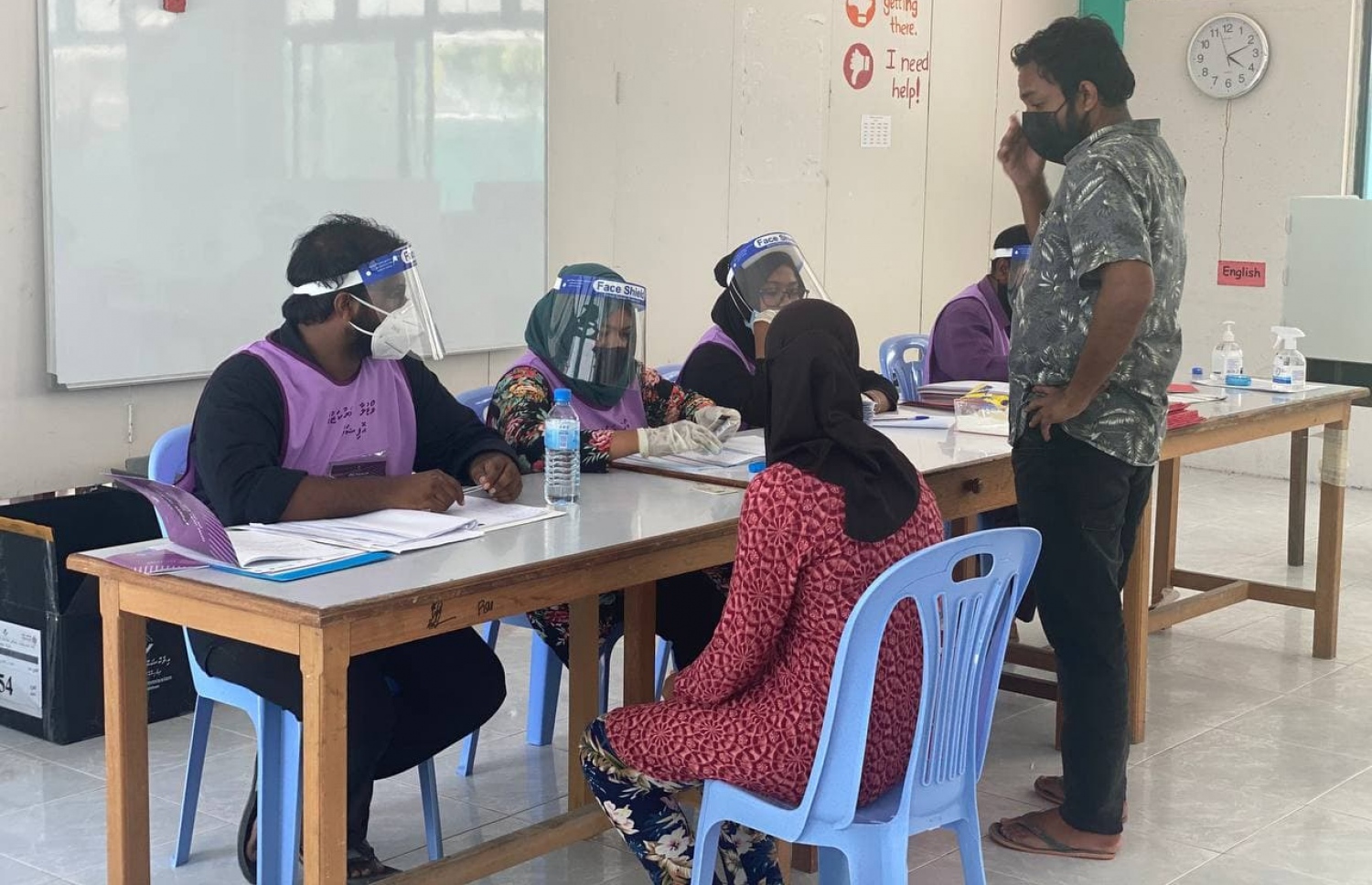 ކ. ހިންމަފުށި: އޭޕްރިލް 10، 2021: ލޯކަލް ކައުންސިލް އިންތިހާބުގައި ހިންމަފުށި ވޯޓުލާ މަރުކަޒުގައި ވޯޓުލުމަށް މީހަކު އޮފިޝަލުންގެ މޭޒު ކައިރީގައި މަޑުކޮށްލައިގެން.-- ފޮޓޯ: ފަރުހާން