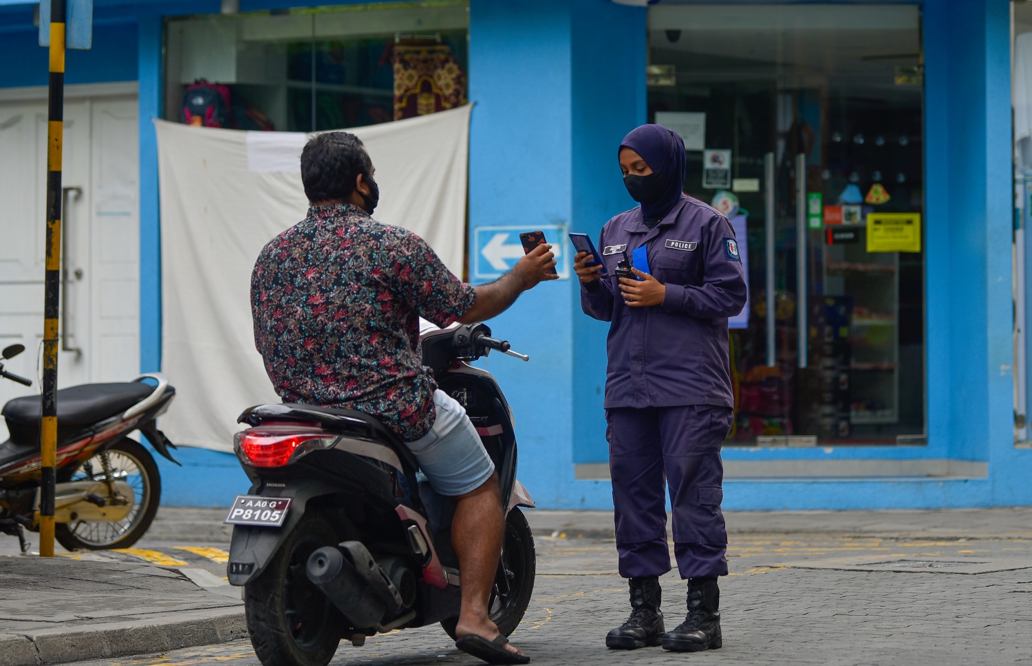 މާލެ- މެއި 13، 2021: ކާފިއު ހިންގާފައި އޮތް އިރު އަންހެން ފުލުހަކު އިއްޔެ މަގުމަތީގައި މީހަކާ ސުވާލުކުރަނީ: -- ފޮޓޯ:އަހުމަދު އަވްޝަން އިލްޔާސް/ މިހާރު