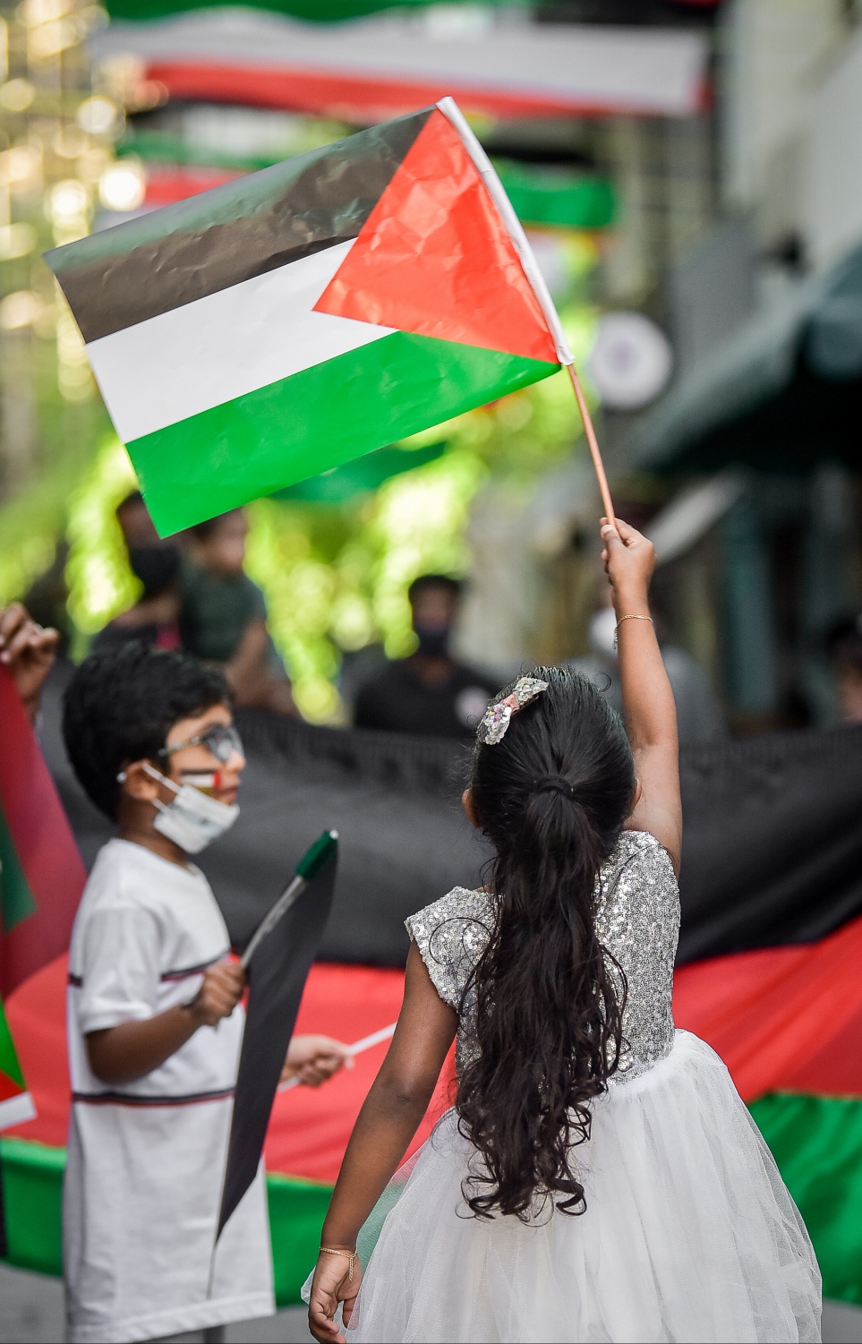 މާލެ- މޭއި 18، 2021: އިޒްރޭލުން ފަލަސްތީނަށް ދޭ ހަމަލާތަކާ ދެކޮޅުހަދައި ފަލަސްތީނާ އެކުގައި ތިބިކަން ހާމަކުރުމަށް ފަލަސްތީނު ދިދަ އާއި ދިވެހި ދިދަ ހިފައިގެން ކުޑަ ކުދިންތަކެއް ގޭގެ ދޮރުމަތީ ޝުއޫރު ފާޅުކުރަނީ --.ފޮޓޯ: ނިޝާން އަލީ/މިހާރު