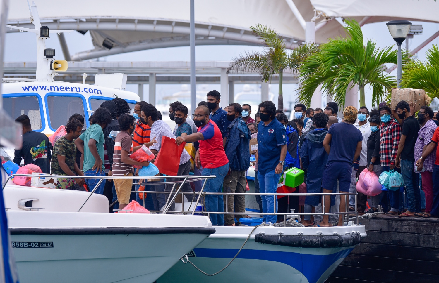 މާލެ އަށް އައި ލޯންޗަކުން ތަކެތި ބަލާ އަރައި ތިބި ބަޔަކު ރަނގަޅަށް މާސްކު އަޅަން ސަމާލުކަން ނުދީ، އެހެން މީހުންގެ ތެރޭގައި ގައިދުރުކަމެއް ނެތި ހަރަކާތްތެރިވަނީ.---ފޮޓޯ: އަހުމަދު އަވްޝަން/މިހާރު