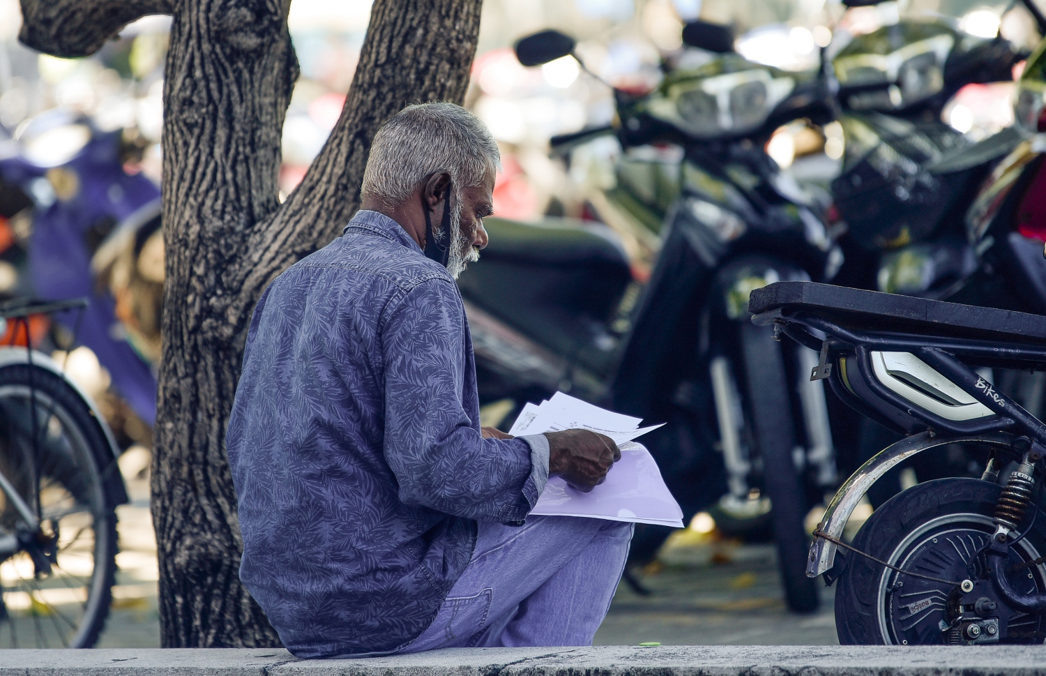 މާލޭގެ ބާޒާރުމަތީގެ ސަރަހައްދުގައި މީހަކު މާސްކު އެޅުމެއް ނެތި، އިށީނދެގެން އިނދެ ބައެއް ޑޮކިއުމަންޓުތައް ބަަލަނީ. ކޮވިޑުން ރައްކާތެރިވާން އެންމެ މުހިންމު އެއް ފިޔަވަޅަކީ މާސްކު އެޅުން.---ފޮޓޯ: އަހުމަދު އަވްޝަން/މިހާރު