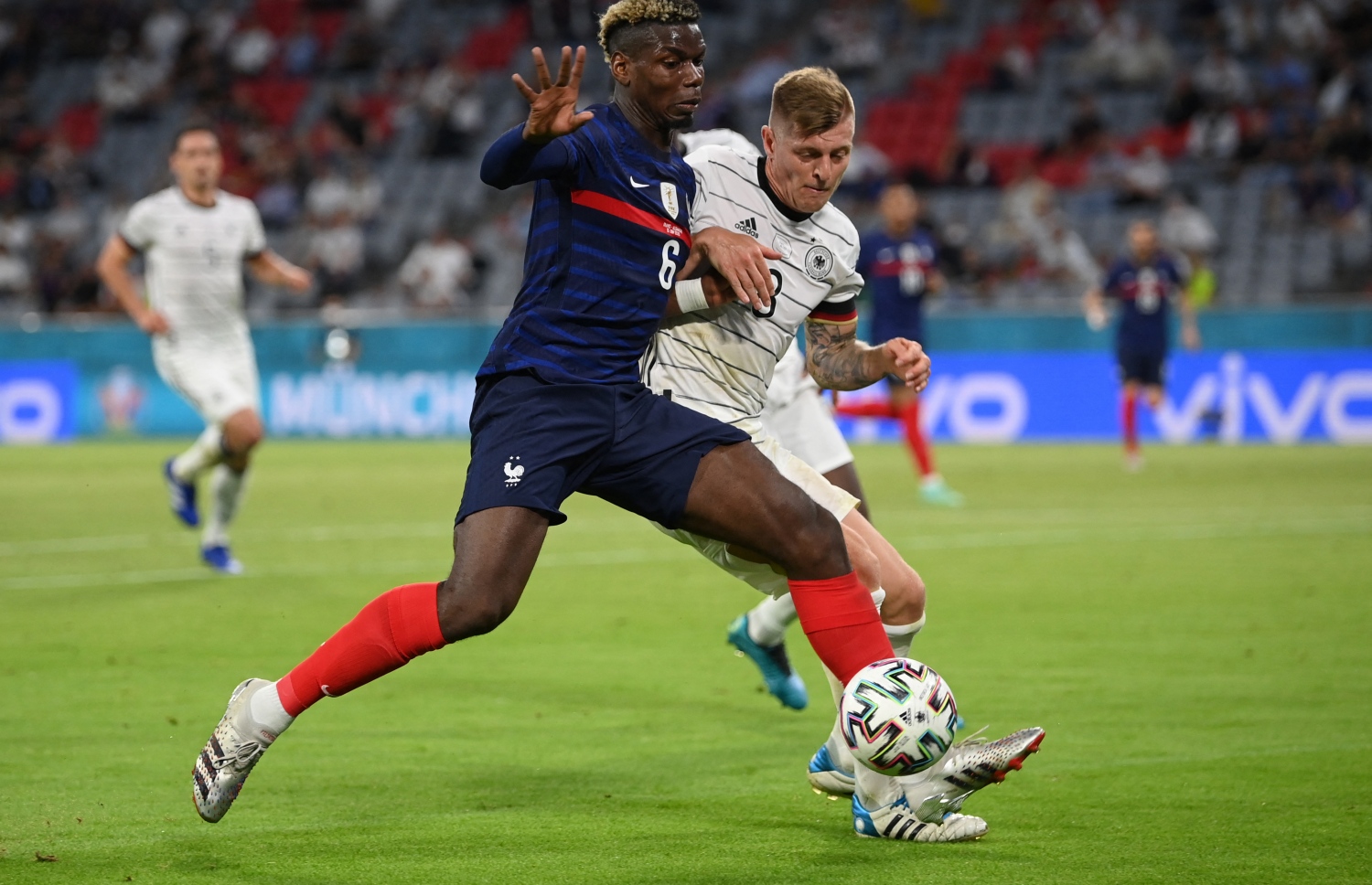 މިއުނިކް: ޖޫން 16، 2021: ޔޫރޯ 2020ގެ ގުރޫޕް އެފްގައި ފްރާންސް އާއި ޖަރުމަން ބައްދަލުކުރި މެޗުގައި ފްރާންސްގެ މިޑްފީލްޑަރު ޕޯލް ޕޮގްބާ ޖެހި ބޯޅައިގެ ފަހަތުން ޖަރުމަނުގެ  މިޑްފީލްޑަރު ޓޯނީ ކްރޫސް ދުވަނީ: މި ޗުގައި ޖަރުމަނު އަތުން 0-1 ން ފްރާންސް ވަނީ ކުރިހޯދާފައި.-- ފޮޓޯ: އޭއެފްޕީ