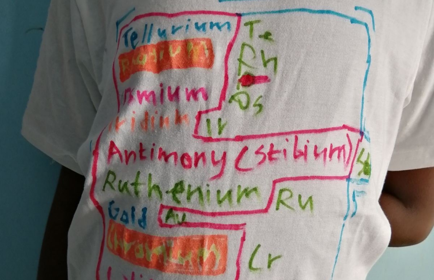 ކެމިސްޓްރީގެ އެލެމެންޓްސްތައް ފެބްރިކް މާކަރު ބޭނުންކޮށްގެން ރަޔާން އޭނާގެ ޓީޝާޓުގައި ލިޔެފައި.