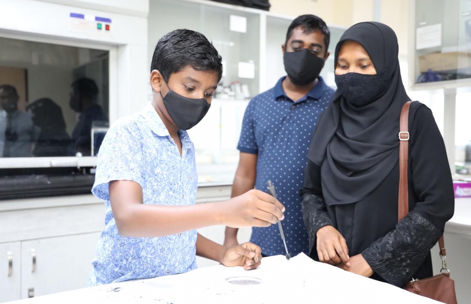 ފުލުހުން ދިން ދައުވަތަކަށް ރަޔާން މަންމަ އާއި ބައްޕައާ އެކު ފުލުހުންގެ ފޮރެންސިކް ލެބުގައި.-- ފޮޓޯ: ޕޮލިސް މީޑިއާ