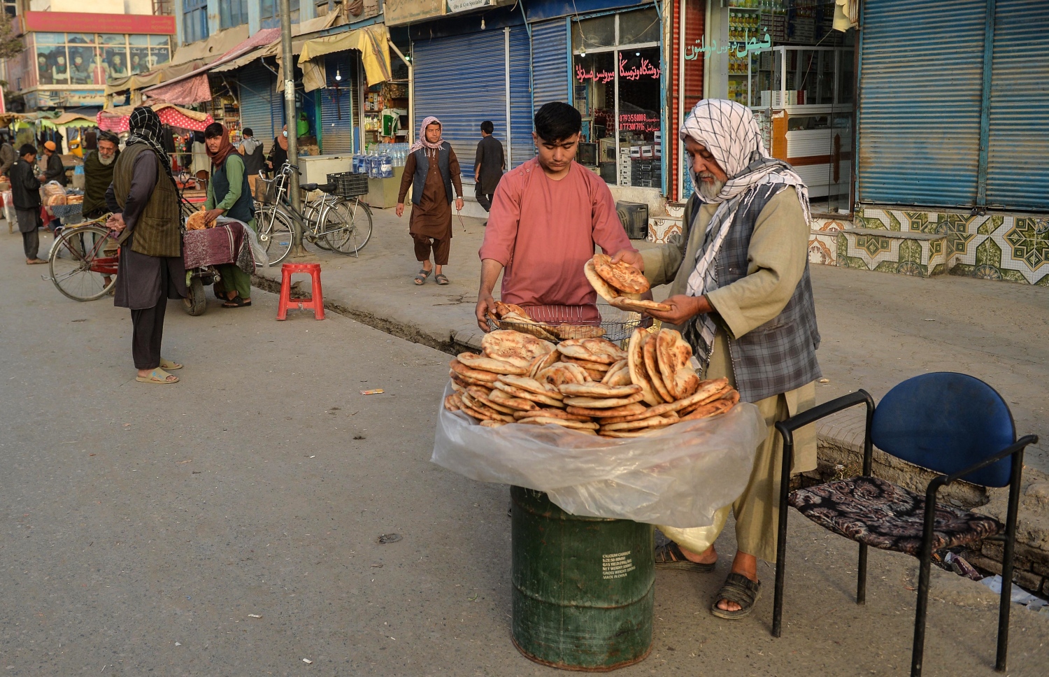 އޮކްޓޫބަރ 10، 2021؛ އަފްގާނިސްތާނުގެ ކުންދޫޒް ޕްރޮވިންސްގައި ބަޔަކު މަގުމަތީގައި ތިބެގެން ރޮއްޓާއި އެކި ބާވަތުގެ ކާބީތަކެތި ވިއްކަނީ. --އޭއެފްޕީ