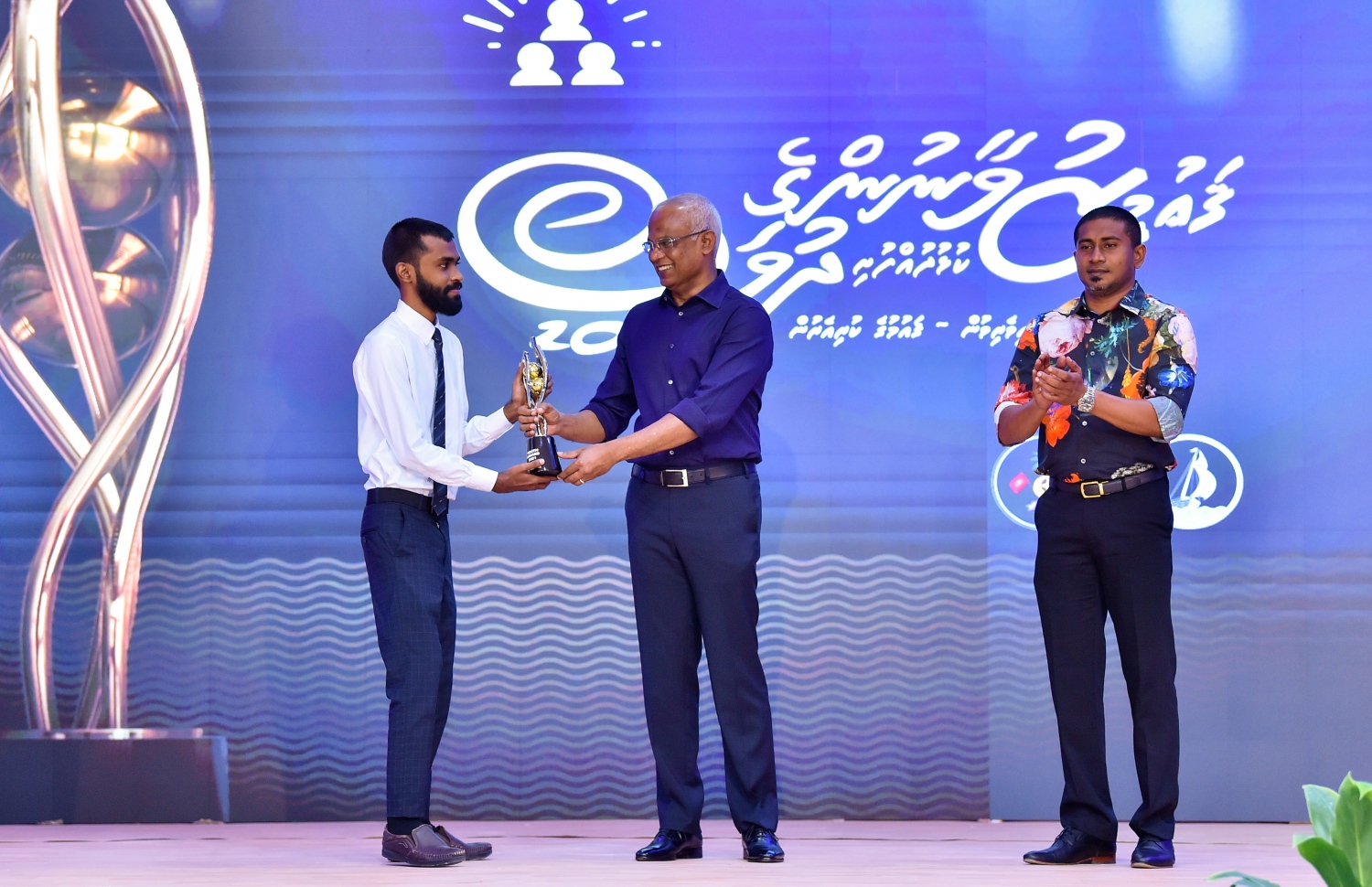 ހދ. ކުޅުދުއްފުށި: އޮކްޓޯބަރު 23، 2021- މި އަހަރުގެ ޒުވާނުންގެ ދުވަހުގެ މުނާސަބަތުގައި ބޭއްވި ޖަލްސާގައި، އާޓް އަދި ފަންނުވެރިކަމުގެ ދާއިރާ އިން ނޫސްވެރިޔާ ނާޒިމް ހަސަނާ، ރައީސް އިބްރާހިމް މުހައްމަދު ސޯލިހު ޒުވާނުންގެ އެވޯޑް ހަވާލު ކޮށްދެއްވަނީ: މި އަހަރު ޒުވާނުންގެ އެވޯޑް 10 މީހަކު ހާސިލުކުރި. ޖަލްސާ ޝަރަފުވެރި ކޮށްދެއްވައި އެވޯޑްތައް ހަވާލު ކޮށްދެއްވީ ރައީސް.---ފޮޓޯ: ރައީސް އޮފީސް