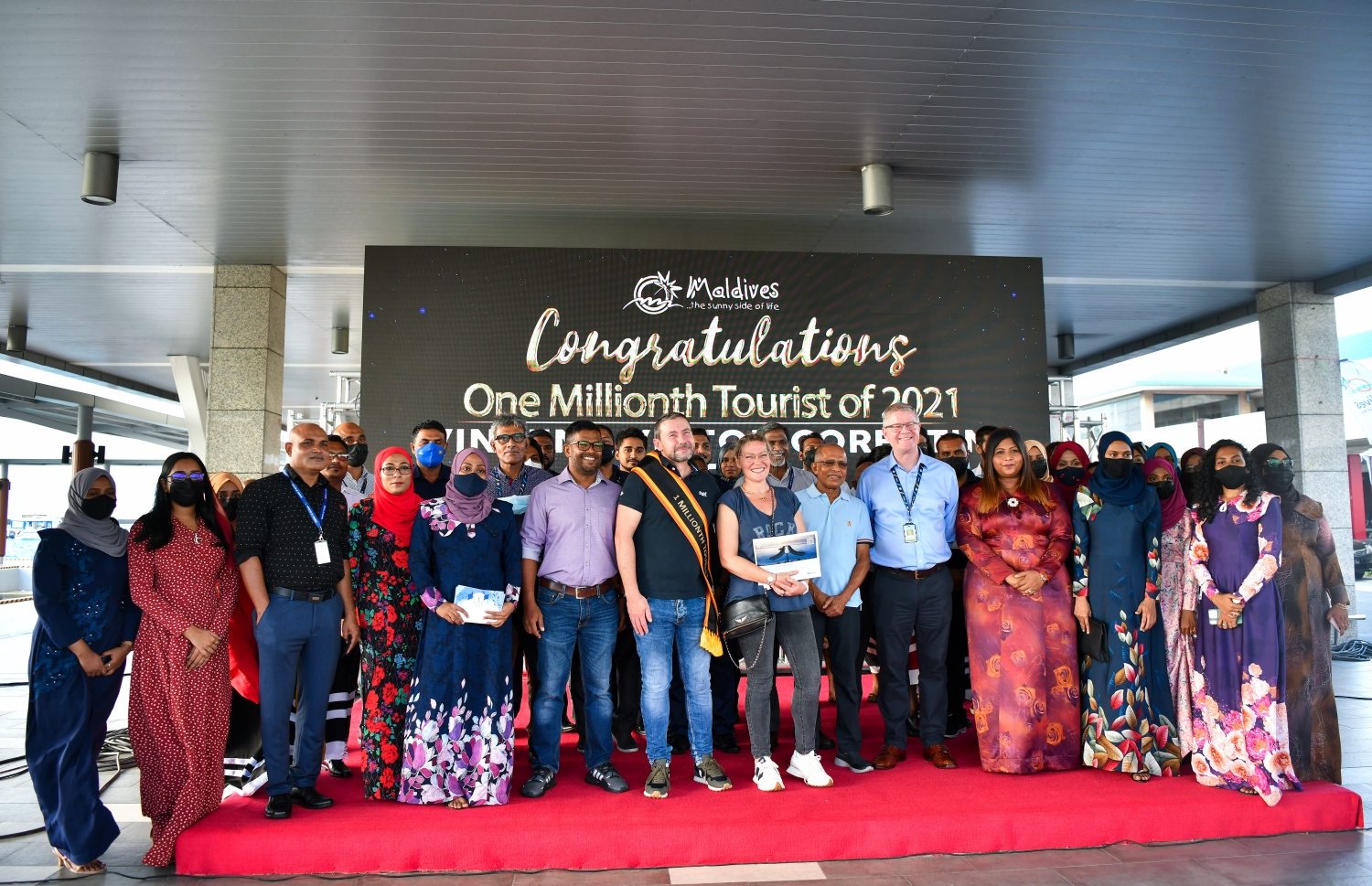 ވެލާނާ އެއާޕޯޓް: އޮކްޓޫބަރު 29، 2021- މި އަހަރު ރާއްޖެ އައި އެއް މިލިއަން ވަނަ ޓޫރިސްޓަކަށް ހޮވި ފްރާންސްގެ ވިންސެންޓް ވިކްޓާ ކޮރެން ޕިޓާއޫ އާއި އޭނާގެ އަންހެނުން، ޓޫރިޒަމް މިނިސްޓްރީ އާއި އެމްއެމްޕީއާރުސީ އާއި އިމިގްރޭޝަނާއި އެމްއޭސީއެލް އަދި މަޓީގެ އިސް ބޭފުޅުންނާ އެކު ފޮޓޯއަކަށް ހުއްޓިގެން-- ފޮޓޯ: ފަޔާޒު މޫސާ / މިހާރު