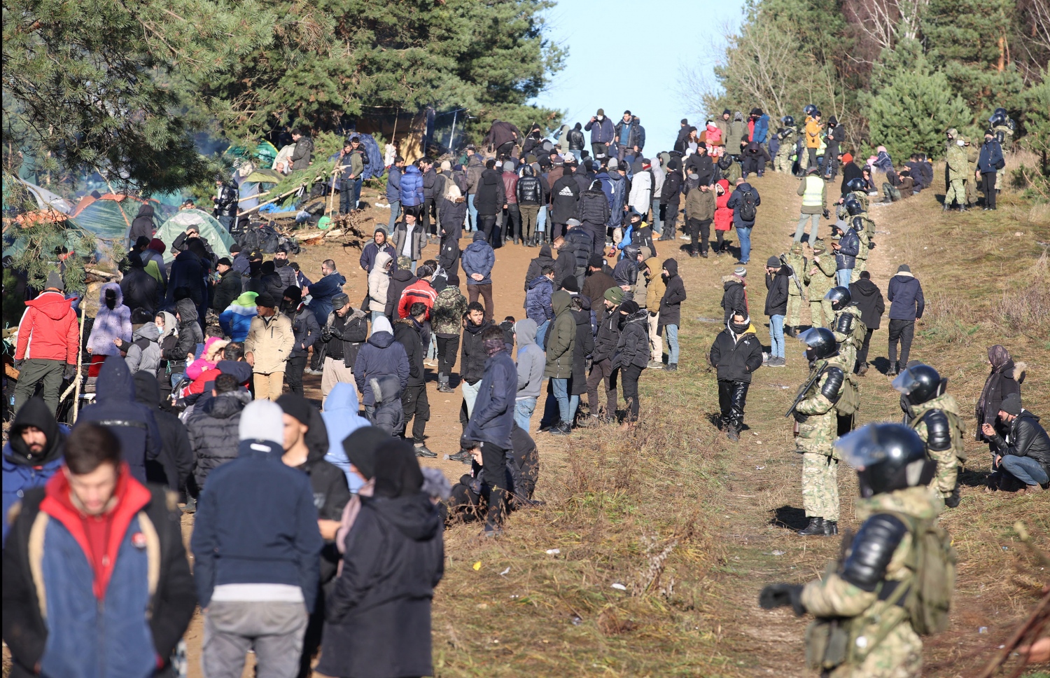 ނޮވެމްބަރު 9، 2021؛ ބެލަރޫސް އާއި ޕޮލެންޑް ގުޅޭ ސަރަހައްދީ ރޮނގު ކައިރިން، ބެލަރޫސްގެ ތެރޭގައި ތިބި ރެފިއުޖީންތަކެއްގެ ކައިރީގައި ބެލަރޫސް ސިފައިން ސަލާމަތީ ކަންތައް ބަލަހައްޓަނީ. --އޭއެފްޕީ