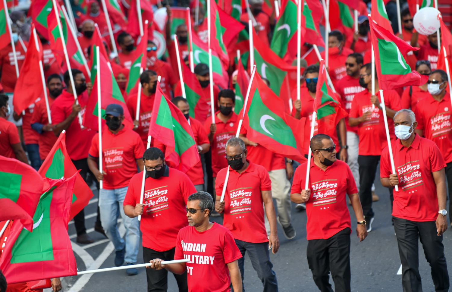 މާލެ- ނޮވެމްބަރު 12، 2021: "މިނިވަންކަމުގެ ދިފާއުގައި" ގެ ނަމުގައި އިދިކޮޅު ކޯލިޝަނުން ބޭއްވި ހިނގާލުމުގެ ބައިވެރިން ރަތްކުލައިގެ ޓީޝާޓު ލައިގެން ގައުމީ ދިދަ ހިފައިގެން ތިބެ، ރާއްޖޭގައި އުޅޭ އިންޑިއާގެ ސިފައިން ފައިބަން ގޮވާލައި އަޑުއުފުލަނީ.---ފޮޓޯ: ފަޔާޒު މޫސާ/ މިހާރު