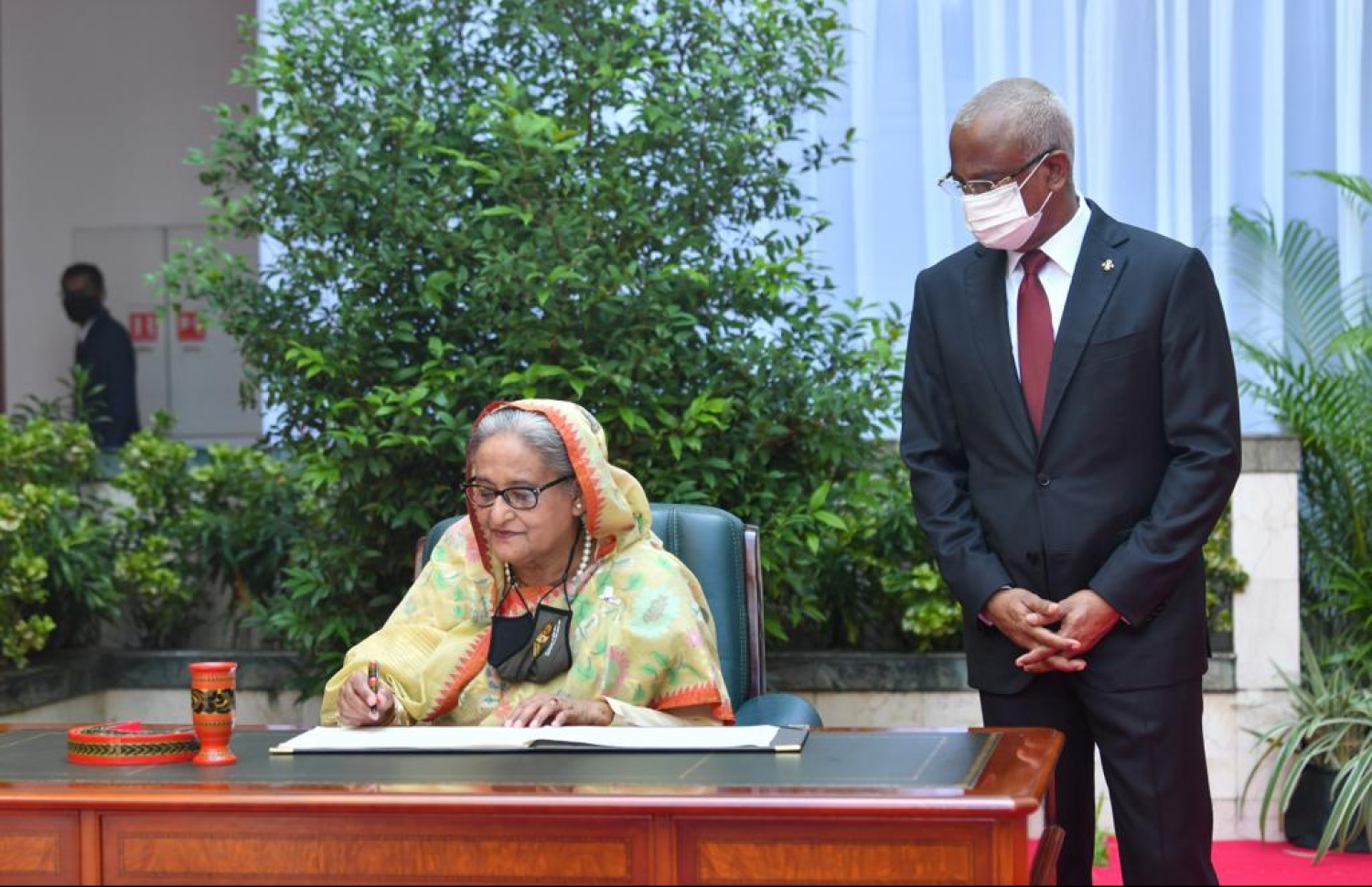 ބަންގްލަދޭޭޝްގެ ބޮޑުވަޒީރު ޝޭޚު ހަސީނާ، ރައީސް އޮފީހުގެ މެހުމާނުން ސޮއިކުރައްވާ ފޮތުގައި ސޮއިކުރައްވާ އިރު، ރައީސް އިބްރާހީމް މުހައްމަދު ސޯލިހު އަރިހުގައި. ފޮޓޯ: ނިޝާން އަލީ/މިހާރު