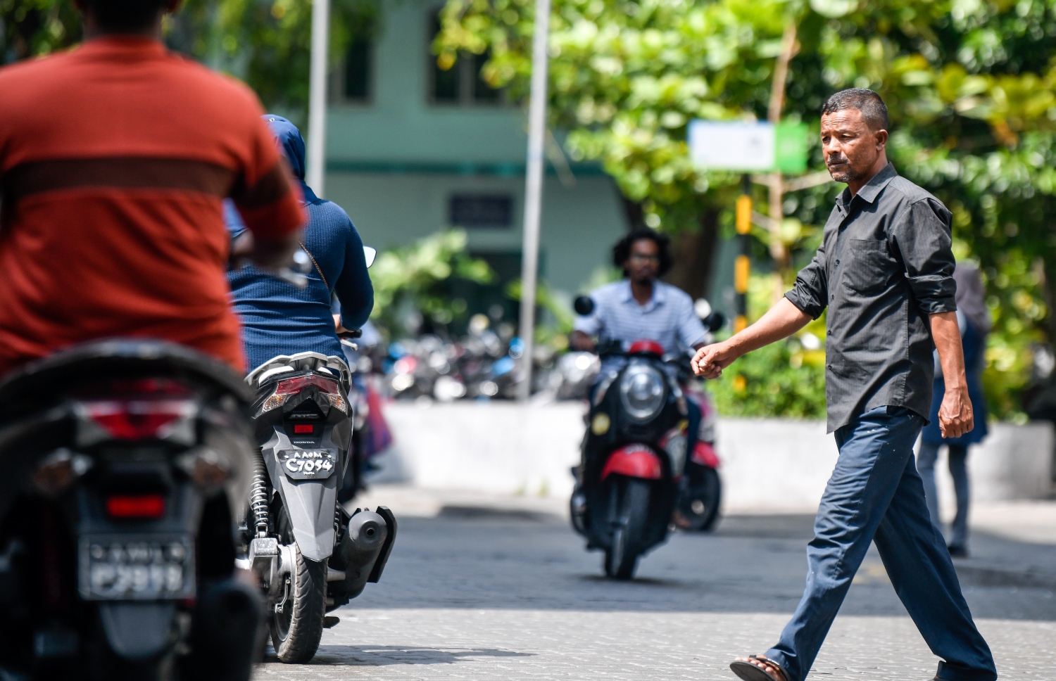 ބާރުބޮޑު މަޖީދީމަގުން ވެހިކަލްތައް ދުއްވާއިރު މީހަކު މަގު ހުރަސްކުރަނީ. މީހުން ގިނައިން އެއްވެ އުޅޭ ތަންތަނުން ވެސް ފެންނަނީ ކޮވިޑްގެ ނުރައްކާ އަނެއްކާ ބޮޑުވާއިރު ވެސް މާކްސް އެޅުމެއް ނެތި އަދި ގައިދުރުކަމެއް ވެސް ނެތި އުޅޭތަން. -- ފޮޓޯ: ފަޔާޒު މޫސާ / މިހާރު