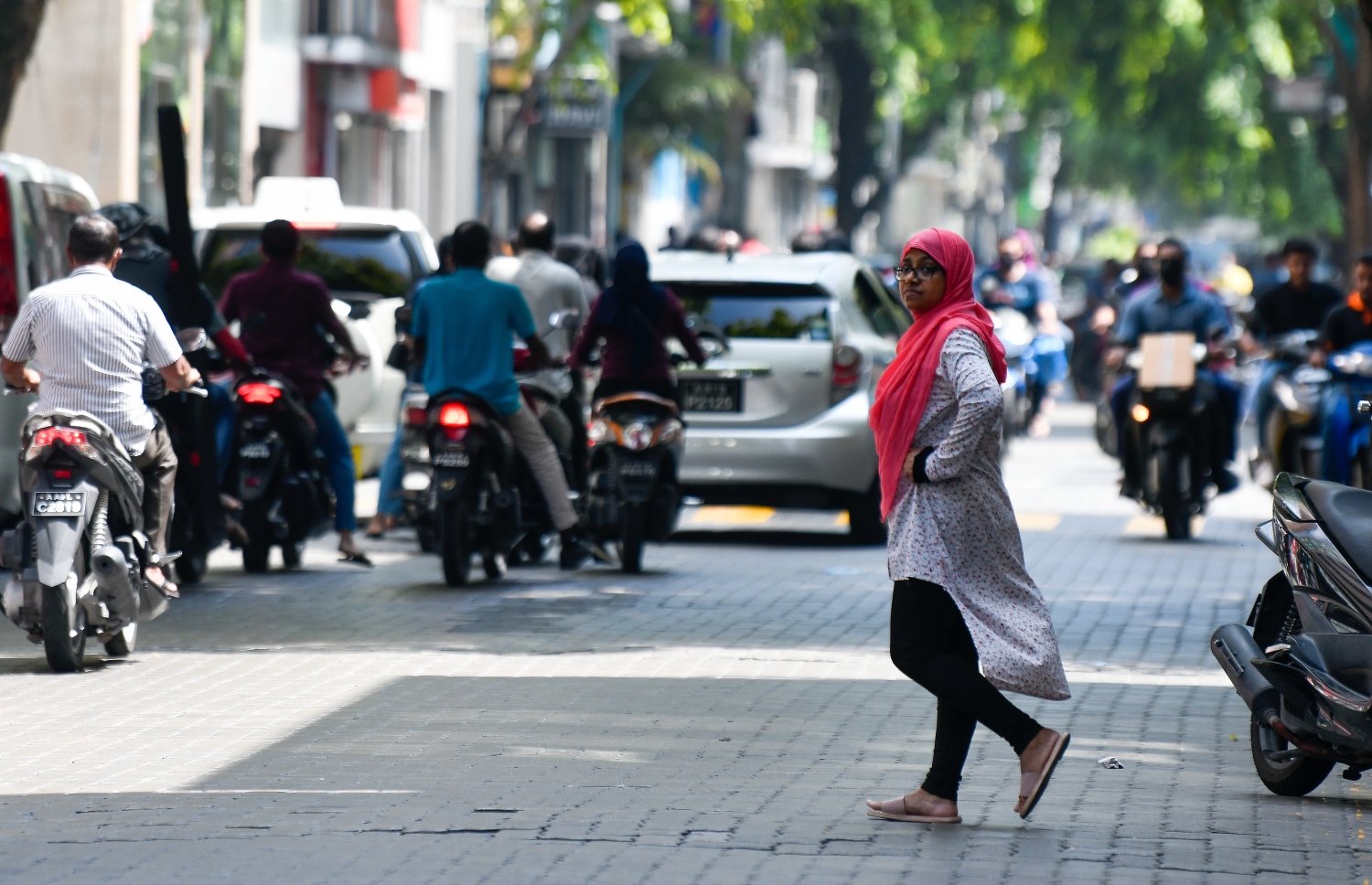 ބާރުބޮޑު މަޖީދީމަގުން ވެހިކަލްތައް ދުއްވާއިރު މީހަކު މަގު ހުރަސްކުރަނީ. މީހުން ގިނައިން އެއްވެ އުޅޭ ތަންތަނުން ވެސް ފެންނަނީ ކޮވިޑްގެ ނުރައްކާ އަނެއްކާ ބޮޑުވާއިރު ވެސް މާކްސް އެޅުމެއް ނެތި އަދި ގައިދުރުކަމެއް ވެސް ނެތި އުޅޭތަން. -- ފޮޓޯ: ފަޔާޒު މޫސާ / މިހާރު
