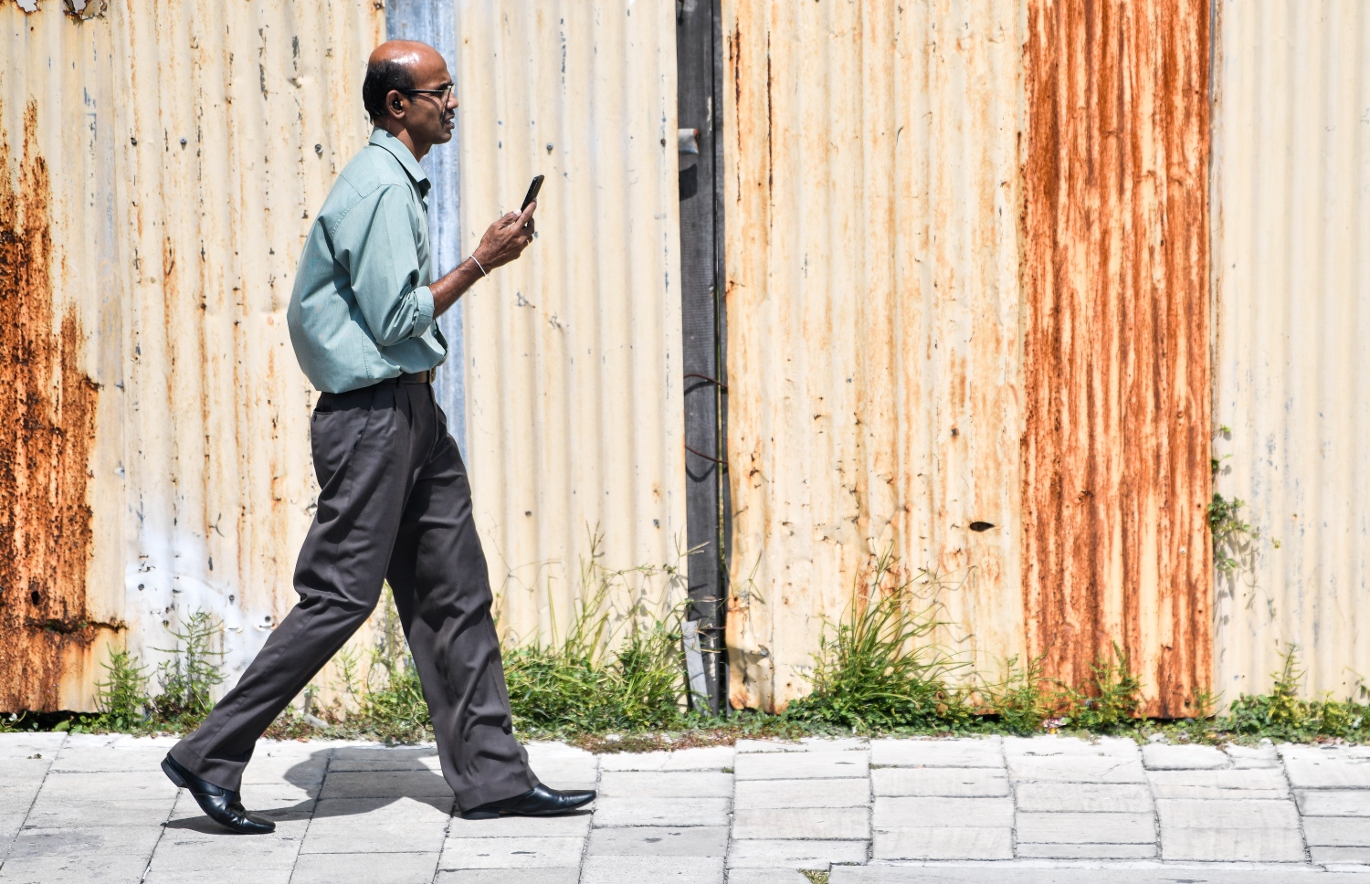 މާސްކް ނާޅާ ހުރި މީހަކު ފޯނާ ކުޅެމުން މަގުމަތިން ހިނގާފައި ދަނީ. -- ފޮޓޯ: ފަޔާޒު މޫސާ / މިހާރު