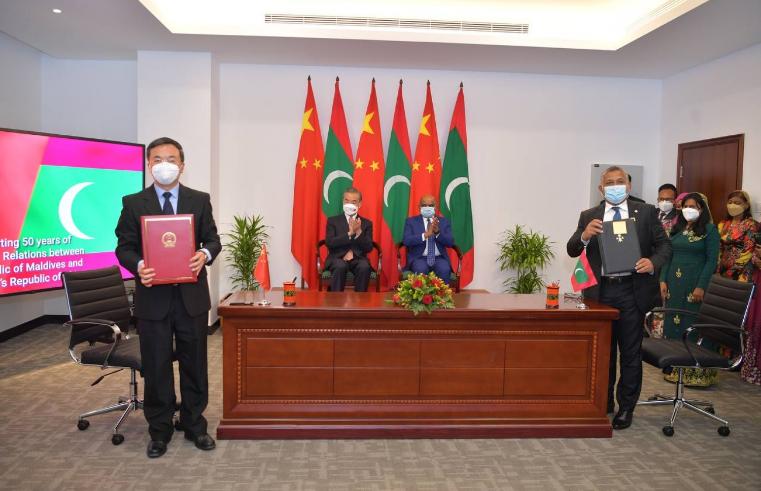 ރާއްޖޭގެ ހައުސިންގެ ދާއިރާ އަށް ޗައިނާ އިން އެހީވުމުގެ އެއްބަސްވުމުގައި ހައުސިން މިނިސްޓަރު އަސްލަމާއި ޗައިނާގެ ސަރުކާރުގެ އިސް އޮފިޝަލަކު ސޮއިކުރެއްވުމަށް ފަހު، ފޮޓޯއަކަށް ހުއްޓިވަޑައިގެން ތިއްބެވިއިރު، ރާއްޖޭގެ ފޮރިން މިނިސްޓަރު ޝާހިދާއި ޗައިނާގެ ފޮރިން މިނިސްޓަރު ވަންގް ޔީ އަތް ޖައްސަވަނީ.---ފޮޓޯ: ފޮރިން މިނިސްޓްރީ