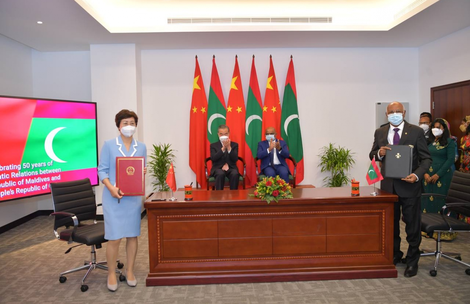 ރާއްޖޭގެ ސިއްހީ ދާއިރާ އަށް ޗައިނާ އިން އެހީވުމުގެ އެއްބަސްވުމުގައި ހެލްތު މިނިސްޓަރު ނަސީމާއި ޗައިނާގެ ސަފީރު ސޮއިކުރެއްވުމަށް ފަހު، ފޮޓޯއަކަށް ހުއްޓިވަޑައިގެން ތިއްބެވިއިރު، ރާއްޖޭގެ ފޮރިން މިނިސްޓަރު ޝާހިދާއި ޗައިނާގެ ފޮރިން މިނިސްޓަރު ވަންގް ޔީ އަތް ޖައްސަވަނީ.---ފޮޓޯ: ފޮރިން މިނިސްޓްރީ